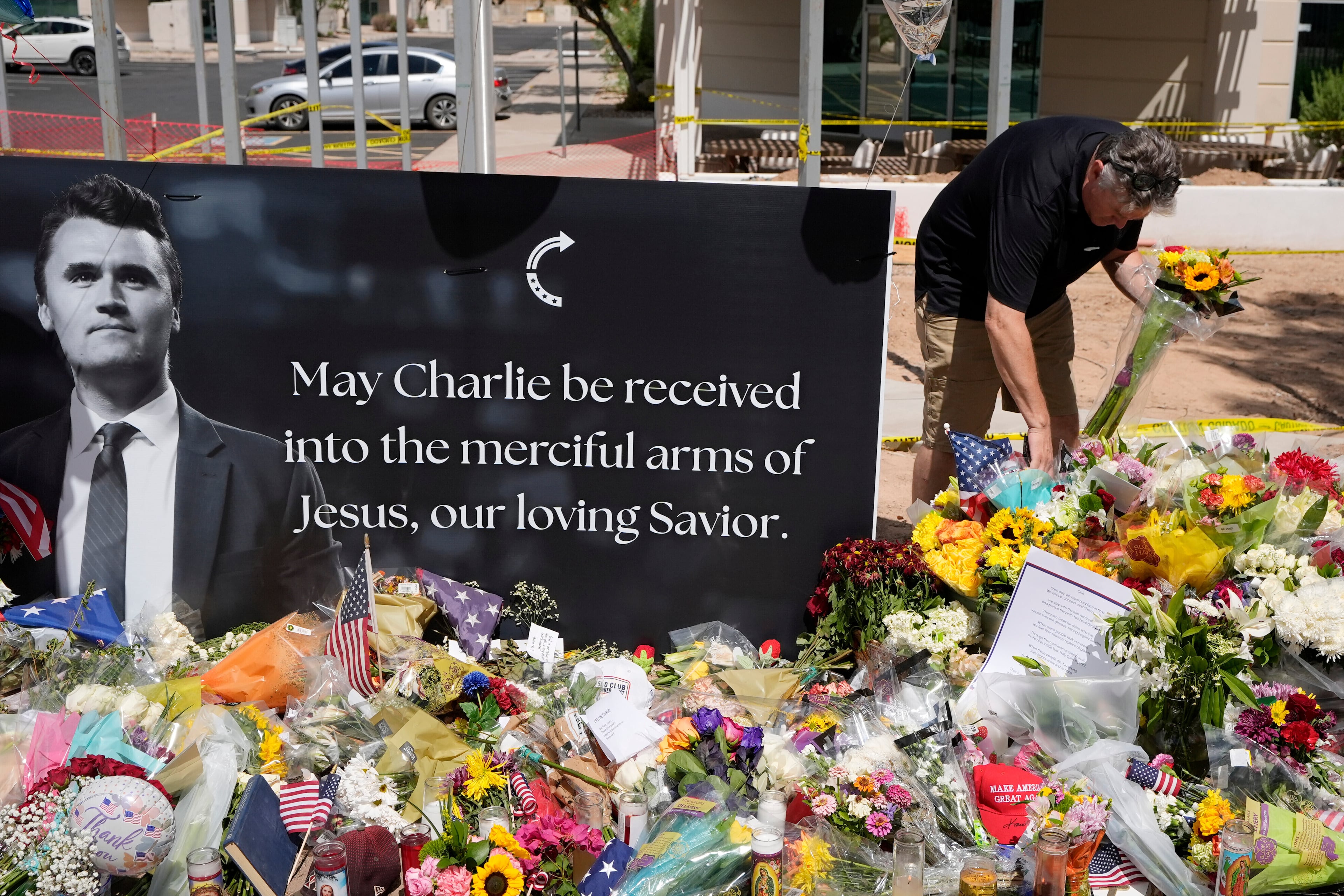 A well-wisher places flowers at a makeshift memorial set up for Charlie Kirk at Turning Point USA headquarters on Thursday, Sept. 11, 2025, in Phoenix. (Ross D. Franklin/AP)