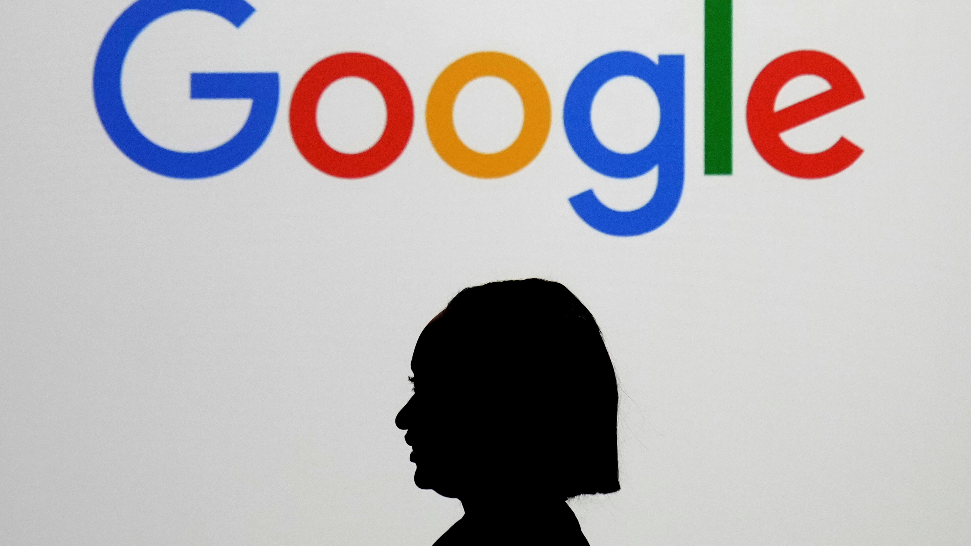 FILE - A woman walks by a giant screen displaying the Google logo at an event at the Paris Google Lab on the sidelines of the AI Action Summit in Paris, Feb. 9, 2025. (AP Photo/Thibault Camus, File)