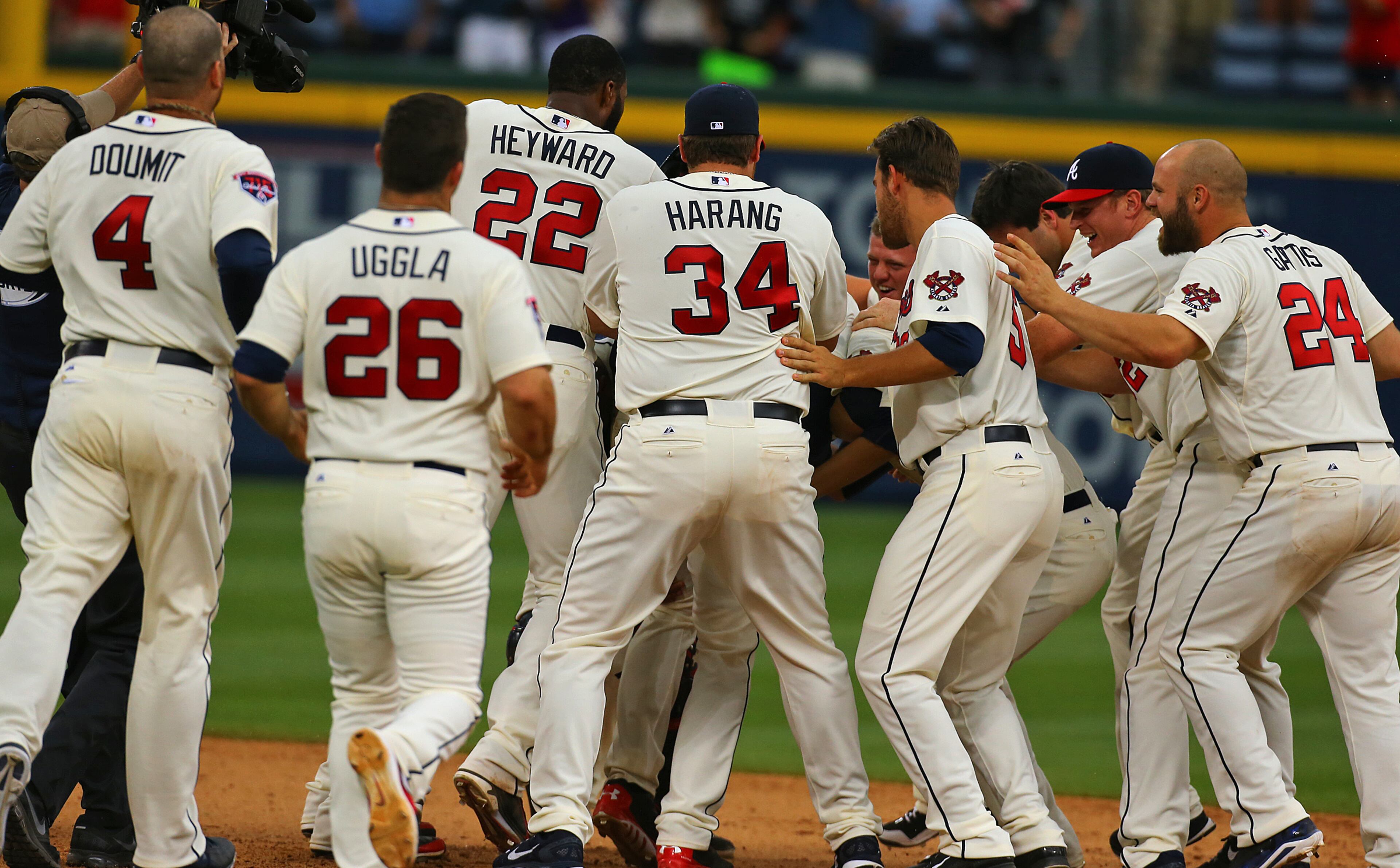 The Braves pile on Freddie Freeman after he hit a game-winning RBI single to beat the Reds 1-0 in the 10th inning of their MLB baseball game on Sunday, April 27, 2014, in Atlanta. CURTIS COMPTON / CCOMPTON@AJC.COM