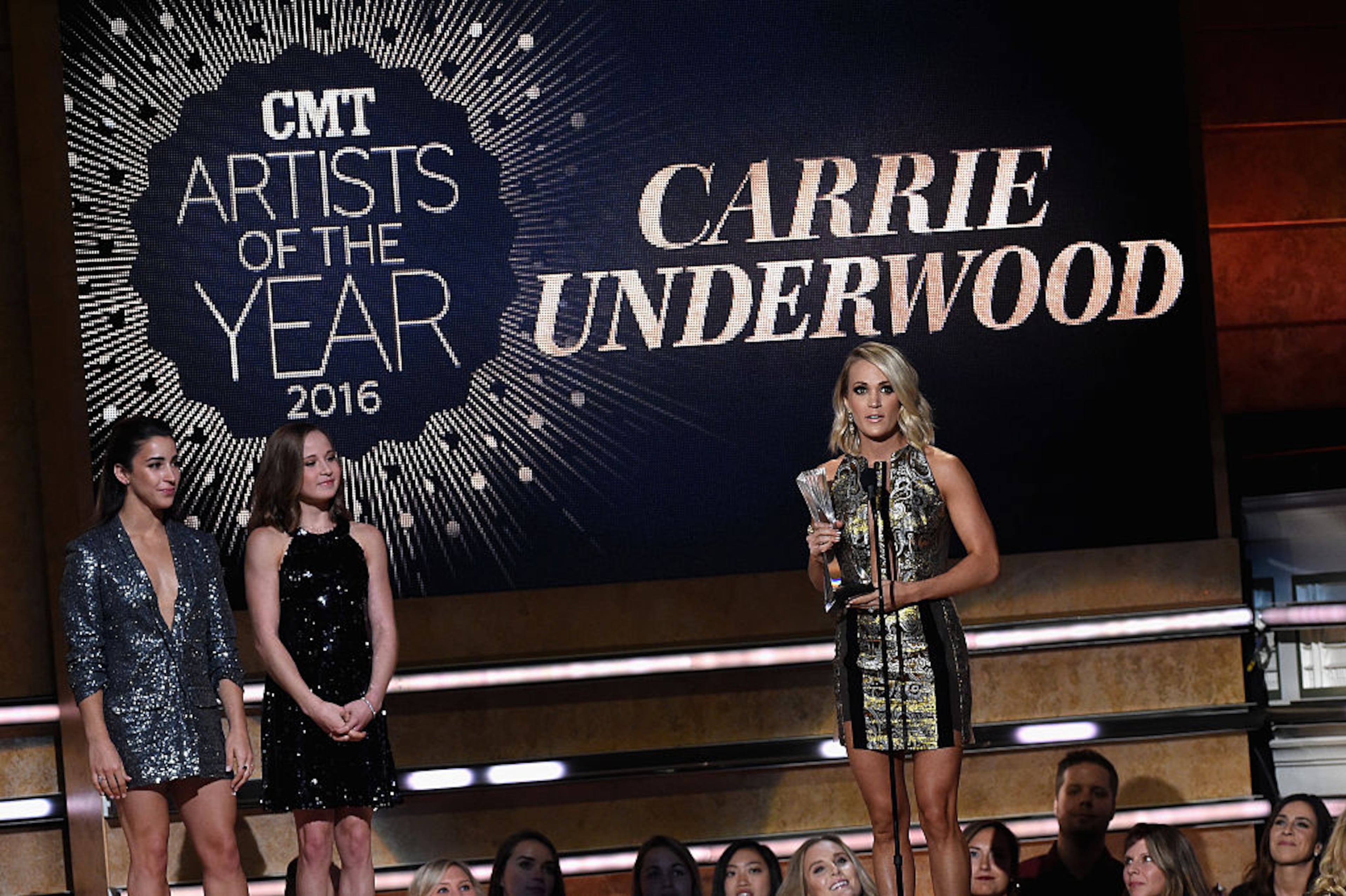 NASHVILLE, TN - OCTOBER 19: Gymnasts Aly Raisman and Madison Kocian present an award on stage to Carrie Underwood at CMT Artists of the Year 2016 on October 19, 2016 in Nashville, Tennessee. (Photo by Rick Diamond/Getty Images for CMT)