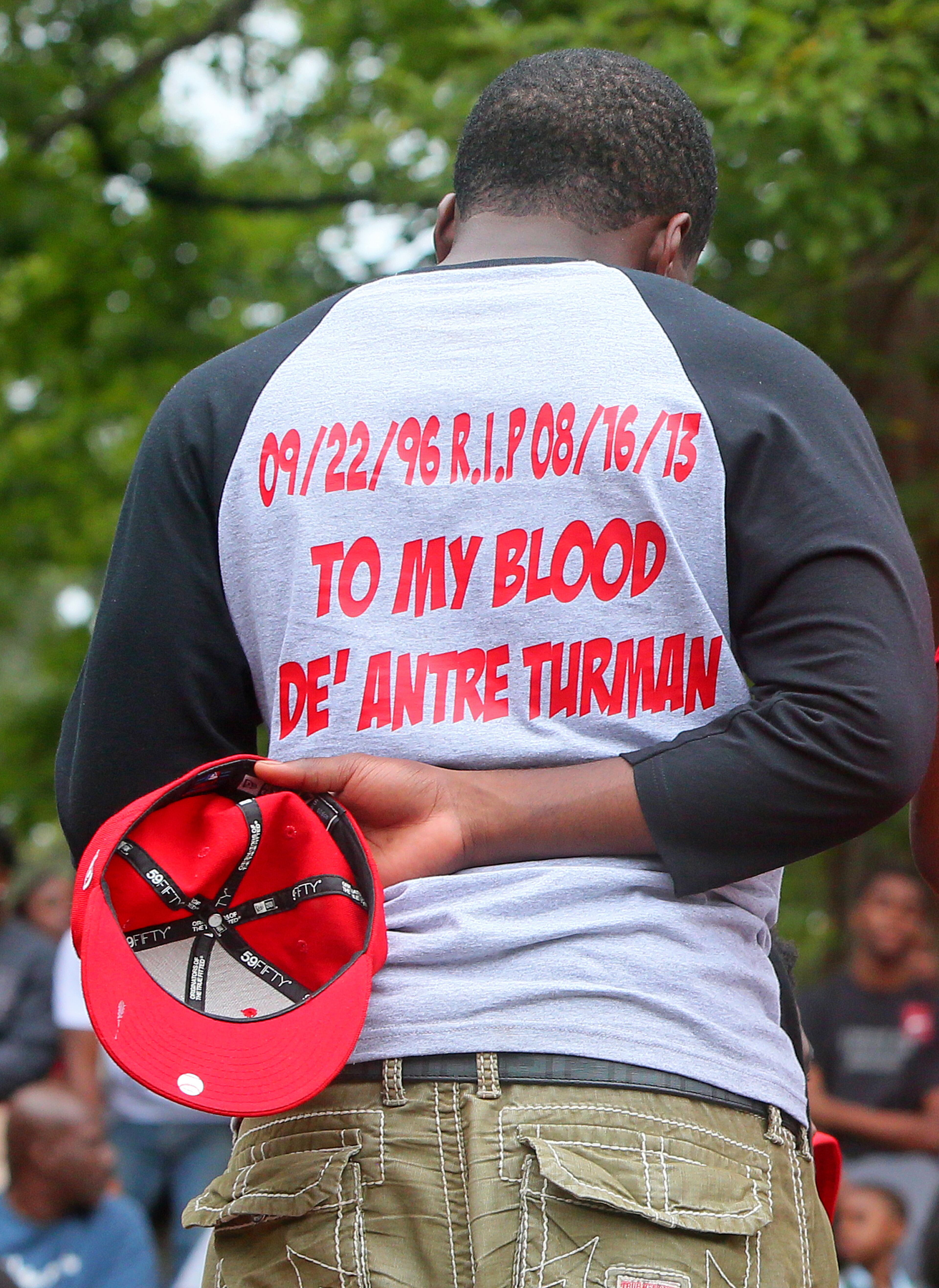 Football teammate Demarcus Morgan removes his hat for a prayer as hundreds gather Sunday night for Creekside High School player De'Antre Turman, a 11th-grader who died from a broken neck suffered during a scrimmage.