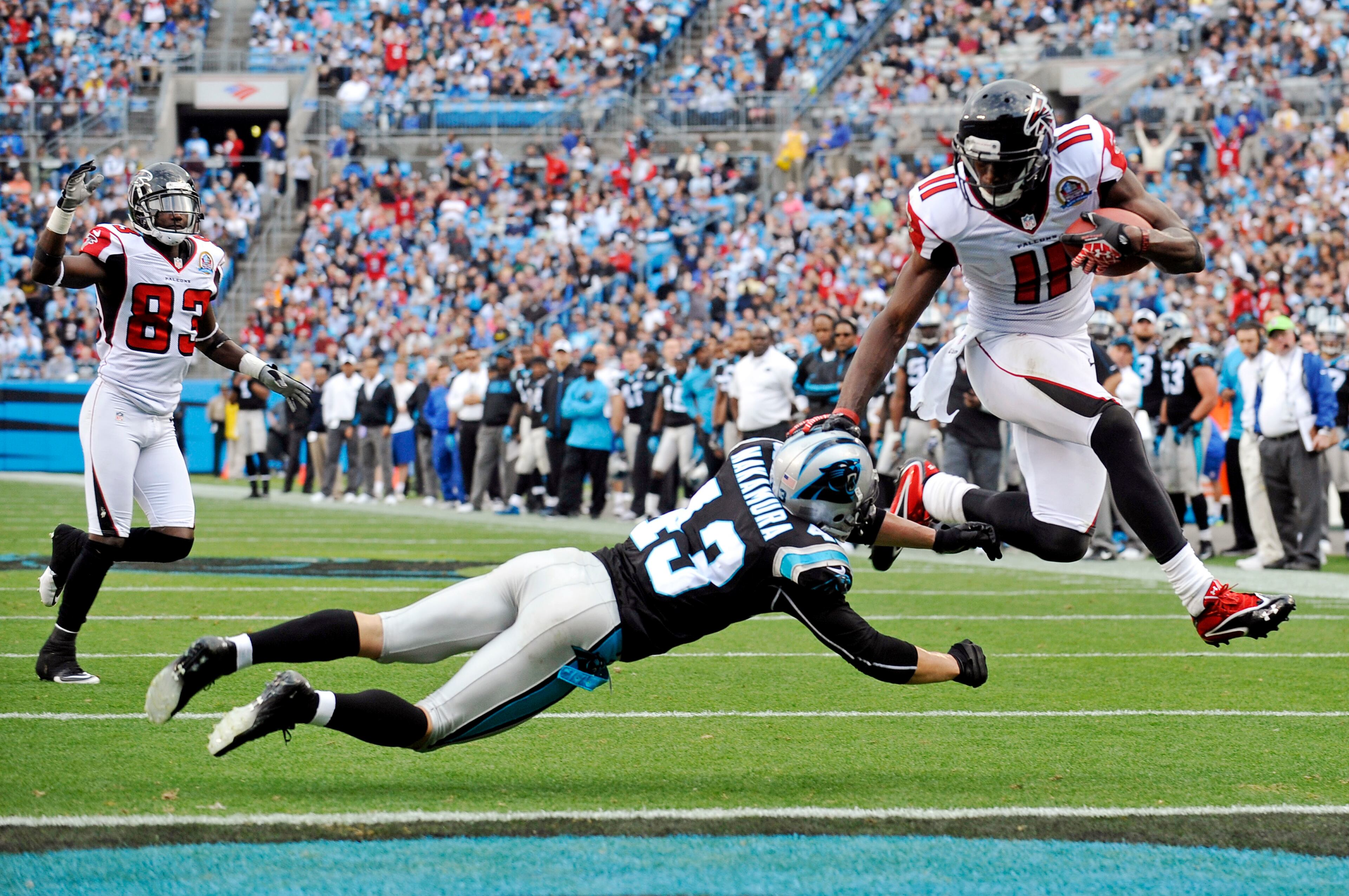 Atlanta Falcons' Julio Jones (11) leaps into the end zone past Carolina Panthers' Haruki Nakamura (43) for a touchdown as Falcons' Harry Douglas (83) watches during the second half of an NFL football game in Charlotte, N.C., Sunday, Dec. 9, 2012. (AP Photo/Rainier Ehrhardt)