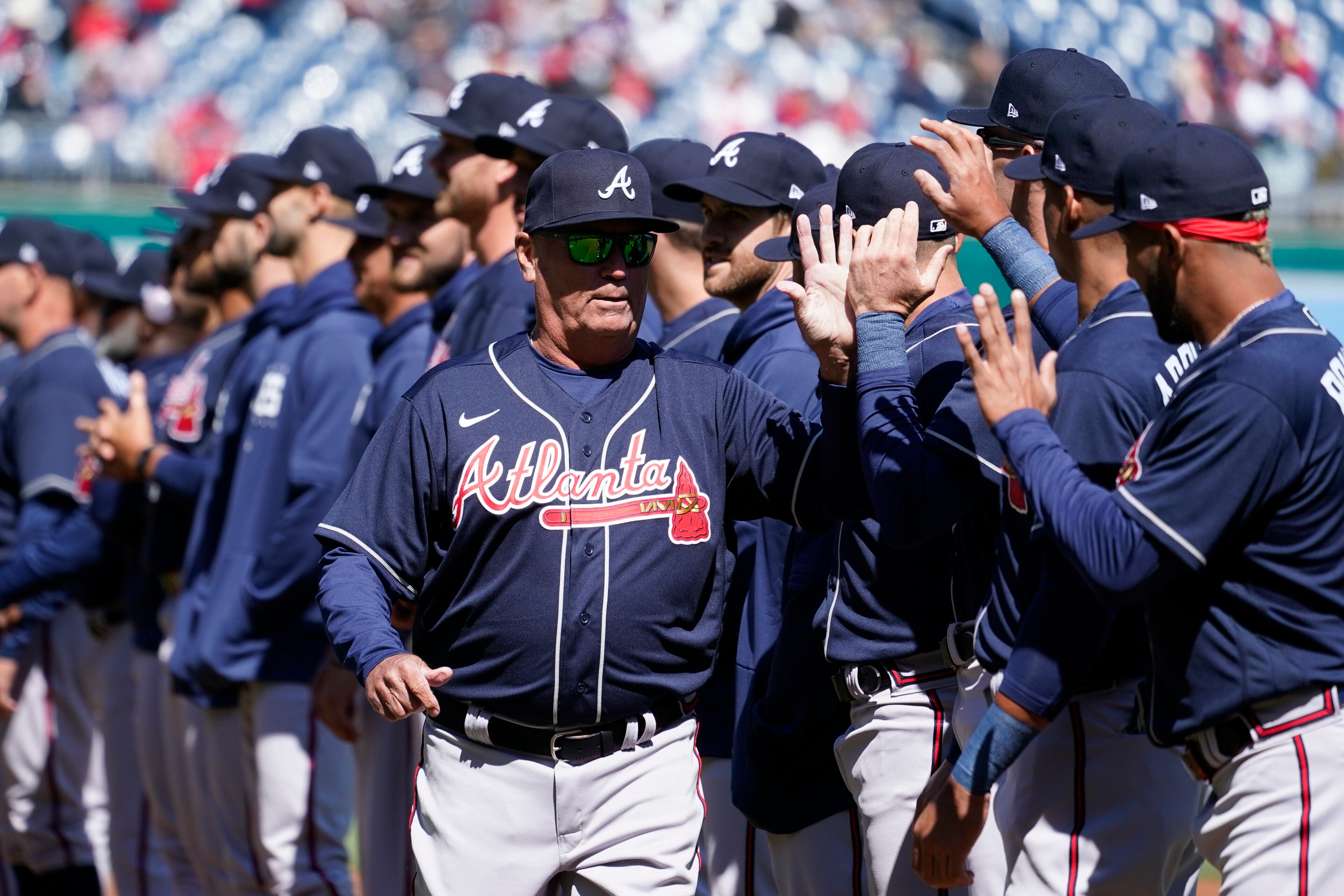 Atlanta Braves manager Brian Snitker high-fives members of the Braves before an opening day baseball game against the Washington Nationals at Nationals Park, Thursday, March 30, 2023, in Washington.