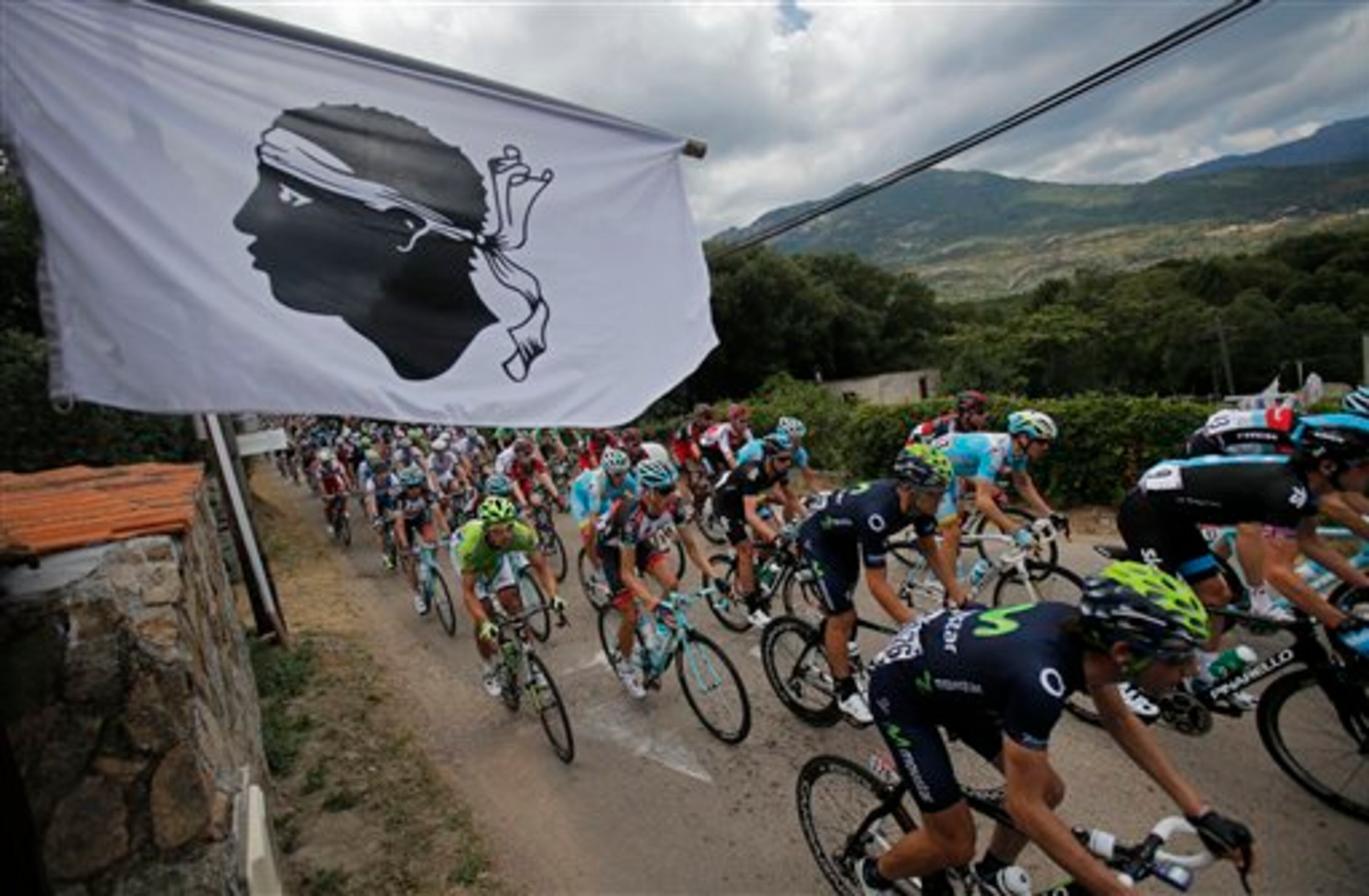 The pack passes a flag featuring a Moor's head, the Corsican emblem, during the first stage of the 100th edition of the Tour de France cycling race over 213 kilometers (133 miles) with start in Porto Vecchio and finish in Bastia, Corsica island, France, Saturday June 29, 2013. (AP Photo/Christophe Ena)