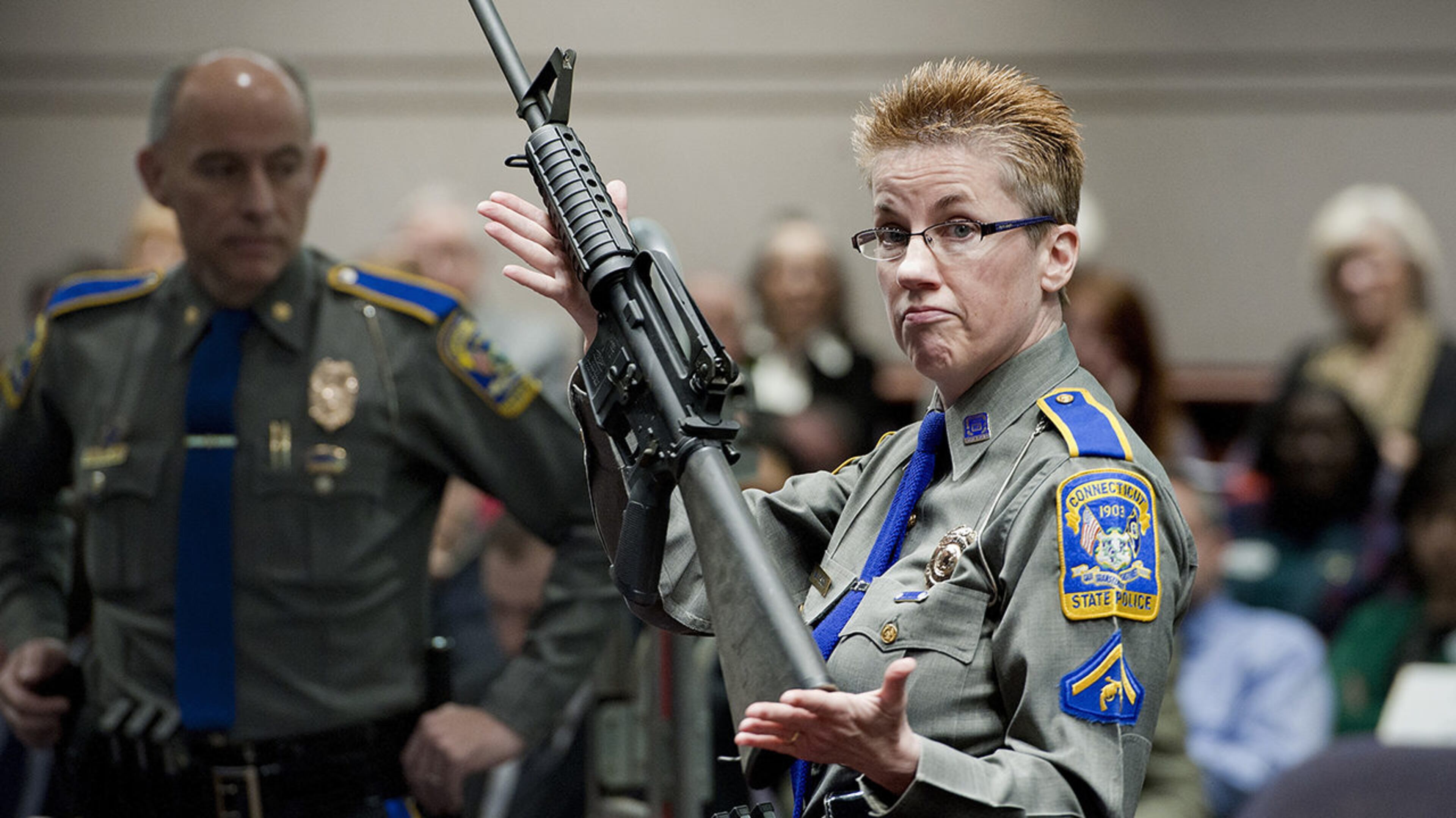 In this Jan. 28, 2013, file photo, firearms training unit Detective Barbara J. Mattson, of the Connecticut State Police, holds up a Bushmaster AR-15 rifle for a demonstration during a hearing at the Legislative Office Building in Hartford, Conn.