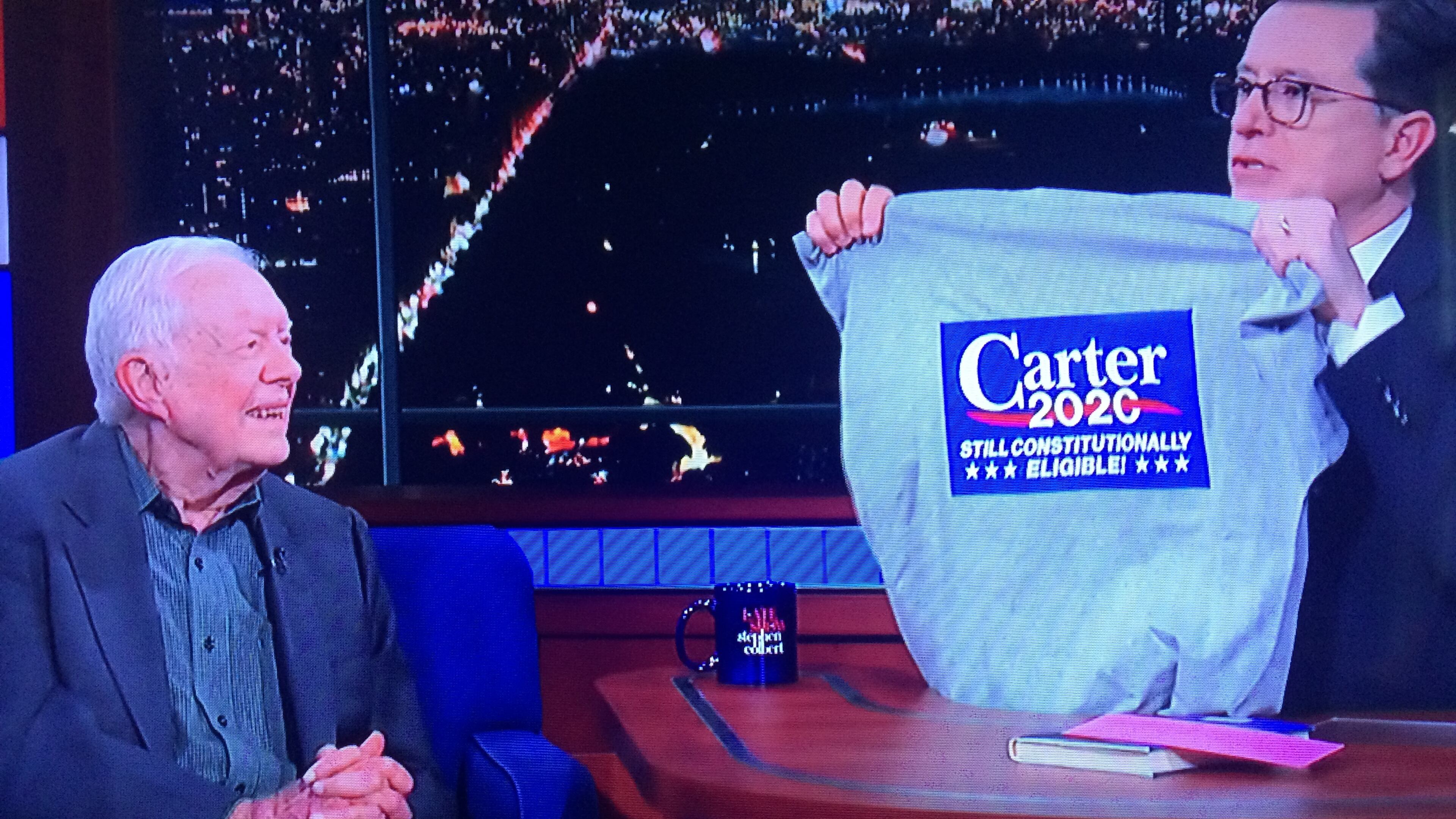 “The Late Show” host Stephen Colbert presents former -- and future? -- President Jimmy Carter with a specially made campaign t-shirt. Courtesy of CBS