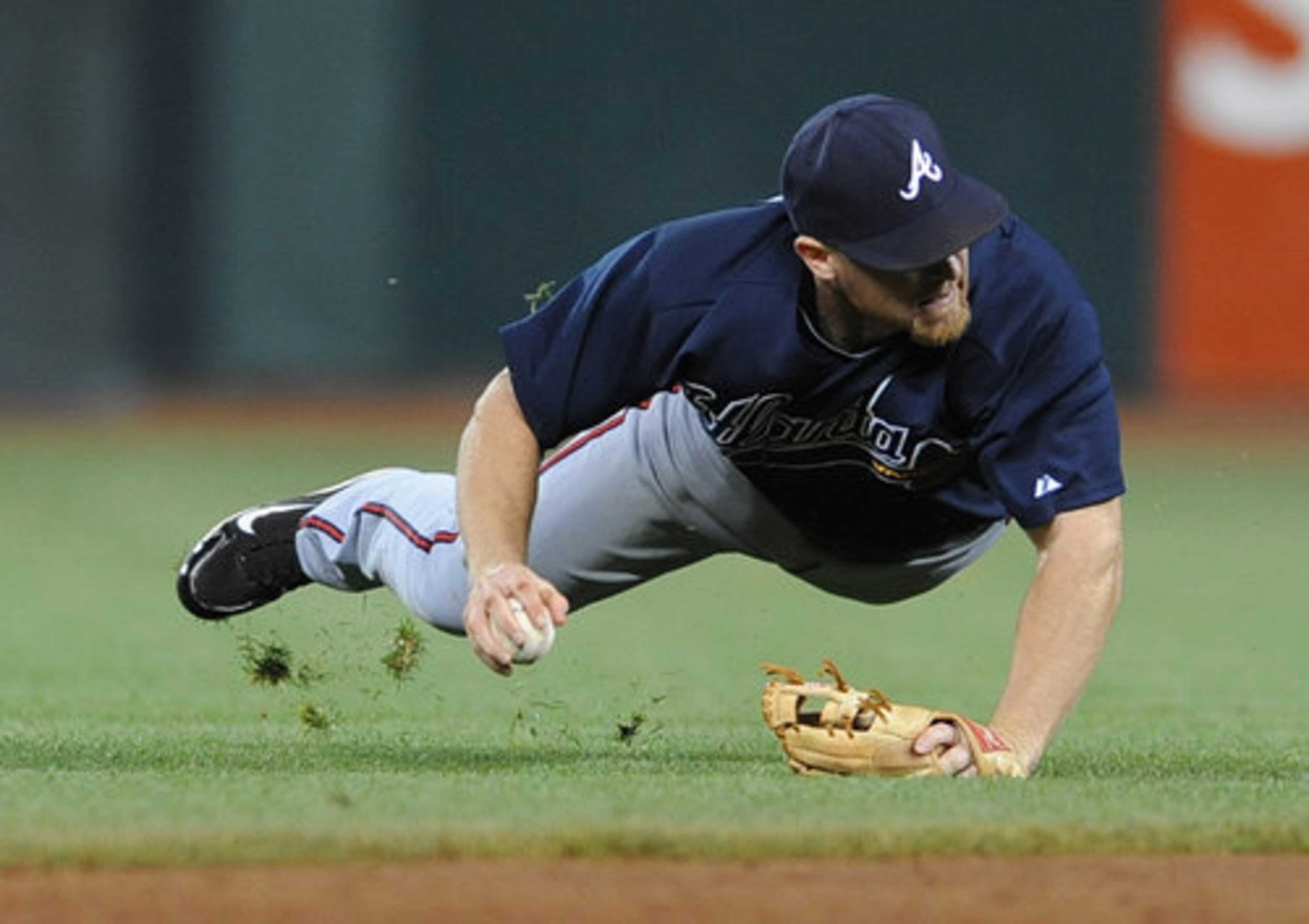 Atlanta Braves second baseman Brooks Conrad goes to the turf to field a grounder by San Francisco Giants' Buster Posey in the third inning of Game 2 of the National League Division Series at AT&T Park in San Francisco, California, on Friday, October 8, 2010. Posey was safe at first base on the play.