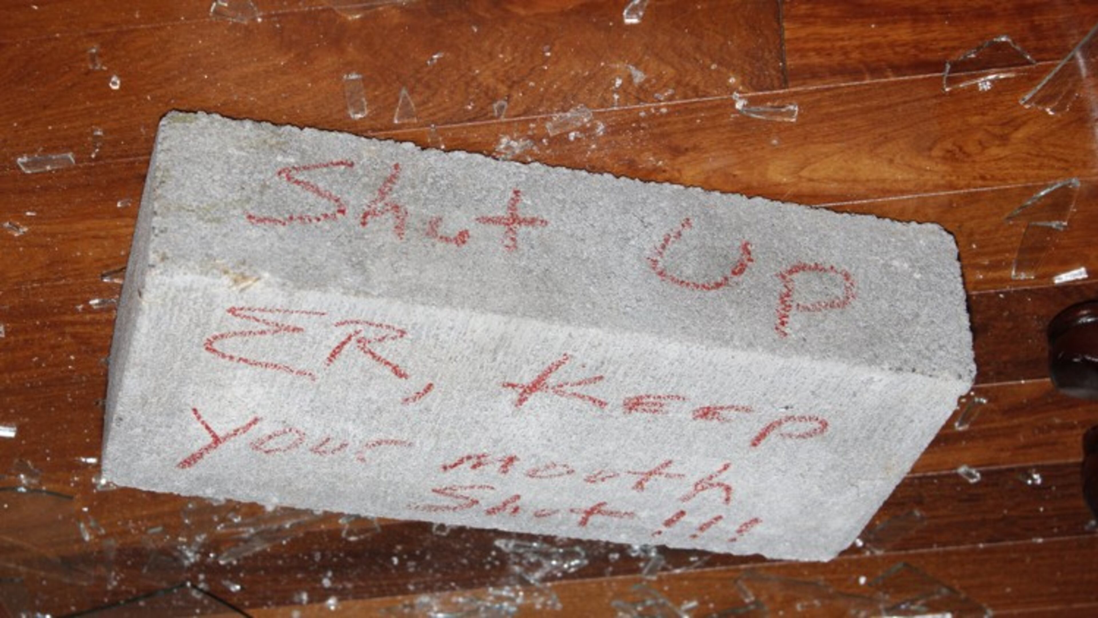 The brick thrown through a window at the home of Elvin "E.R." Mitchell, a contractor who has pleaded guilty to conspiracy to commit bribery and has agreed to cooperate with the on-going investigation.