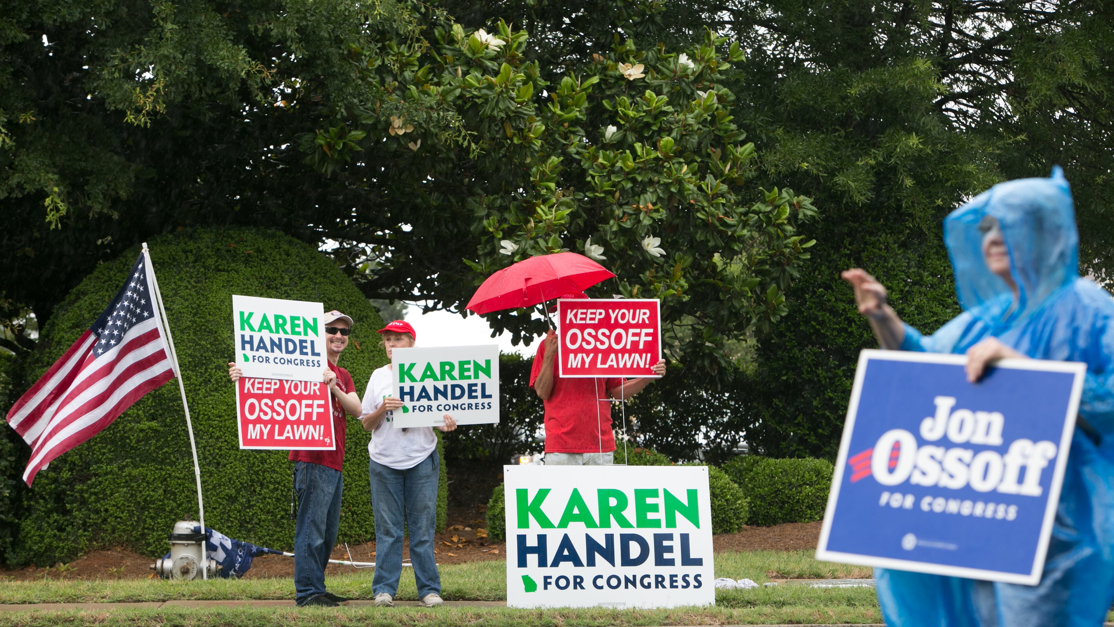 Supporters of Democrat Jon Ossoff and Republican Karen Handel brave the rain Tuesday. (Credit: Jessica McGowan / Getty Images)