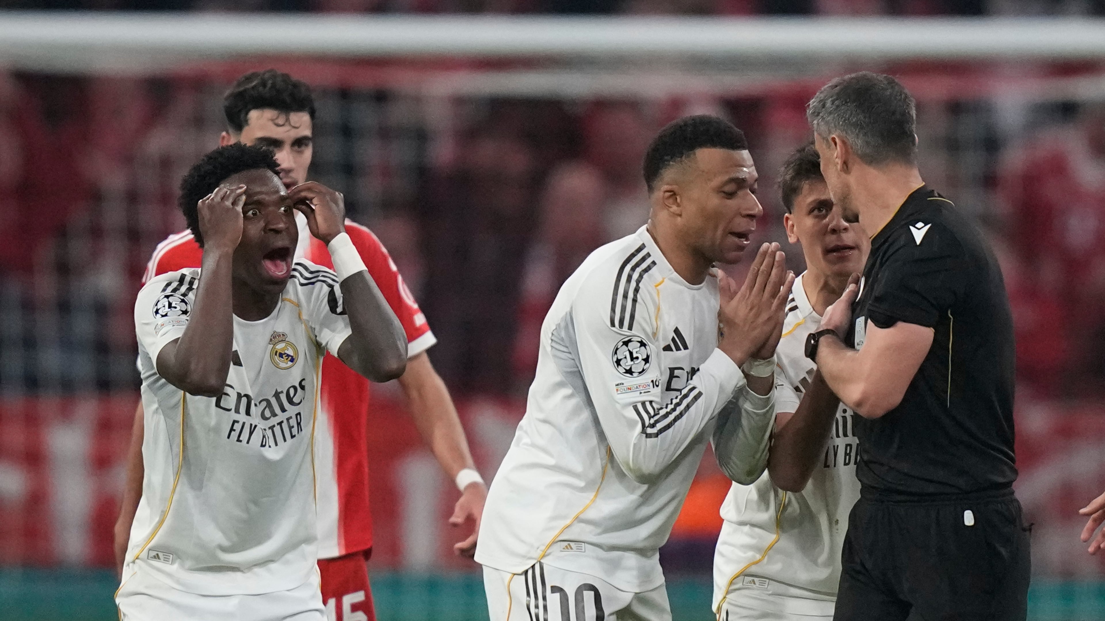 Real Madrid's Kylian Mbappe, center, and Vinicius Jr., left, disagree with referee Slavko Vincic during the Champions League quarterfinal second leg soccer match between Bayern Munich and Real Madrid in Munich, Germany, Wednesday, April 15, 2026. (AP Photo/Matthias Schrader)