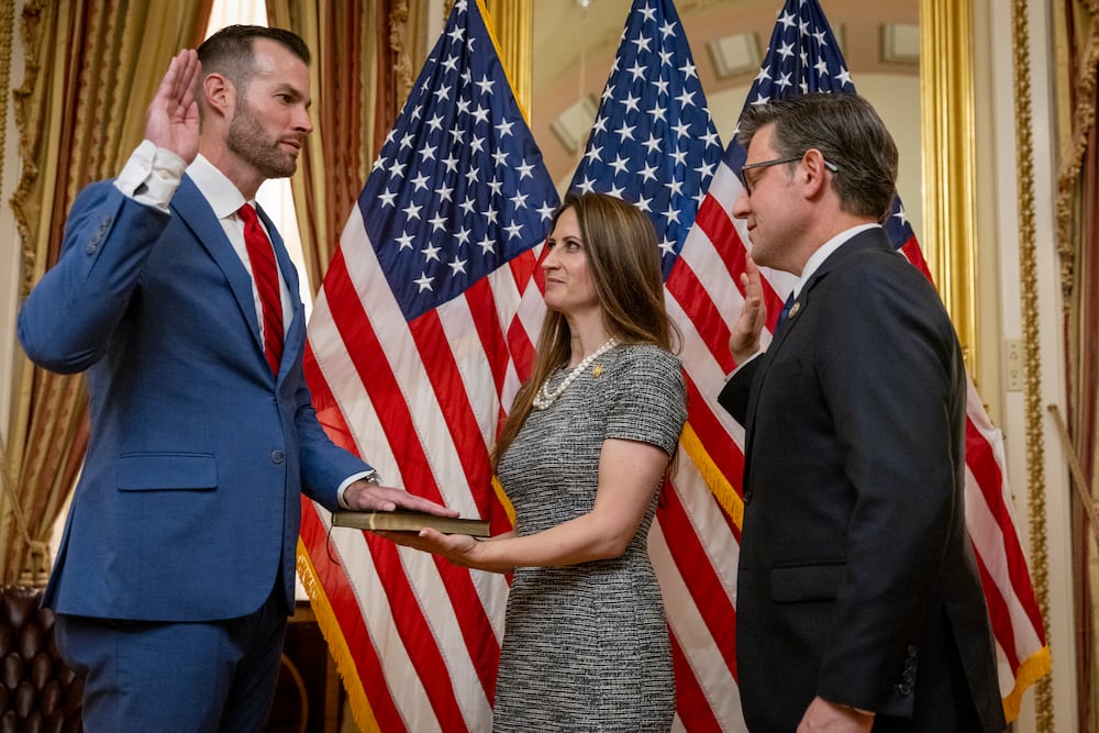 Speaker of the House Mike Johnson (right) administers the oath of office to U.S. Rep. Clay Fuller during a ceremonial swearing-in on Capitol Hill in Washington. Fuller's wife, Kate, holds the Bible. (Nathan Posner for the AJC)