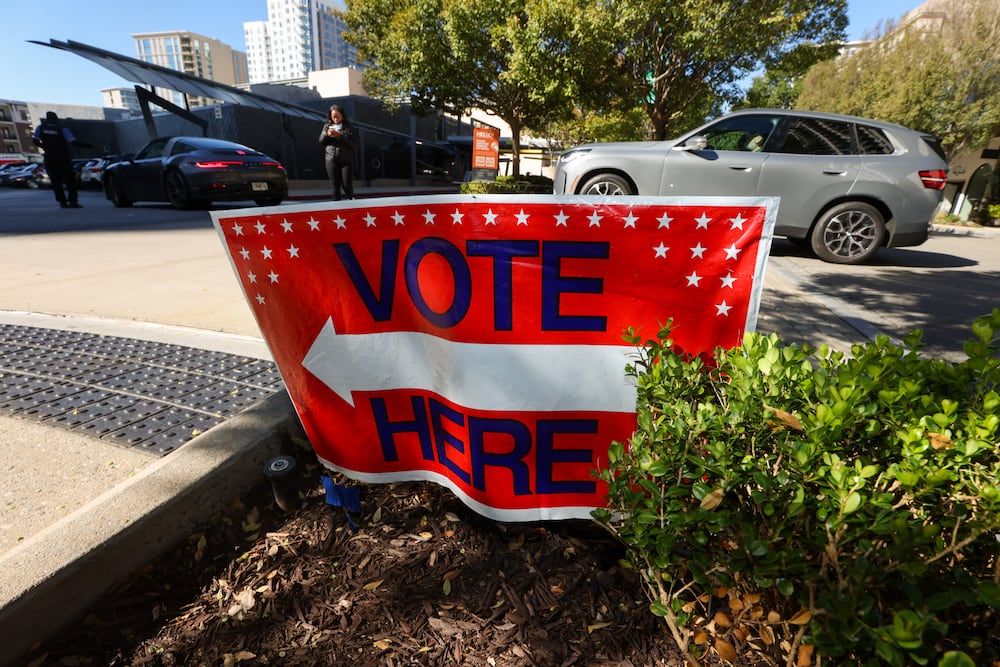 Drivers enter the parking lot for the Buckhead Library as a "Vote Here" sign is posted at the entrance during early voting for the Georgia general election last week in Atlanta. (Jason Getz/AJC)