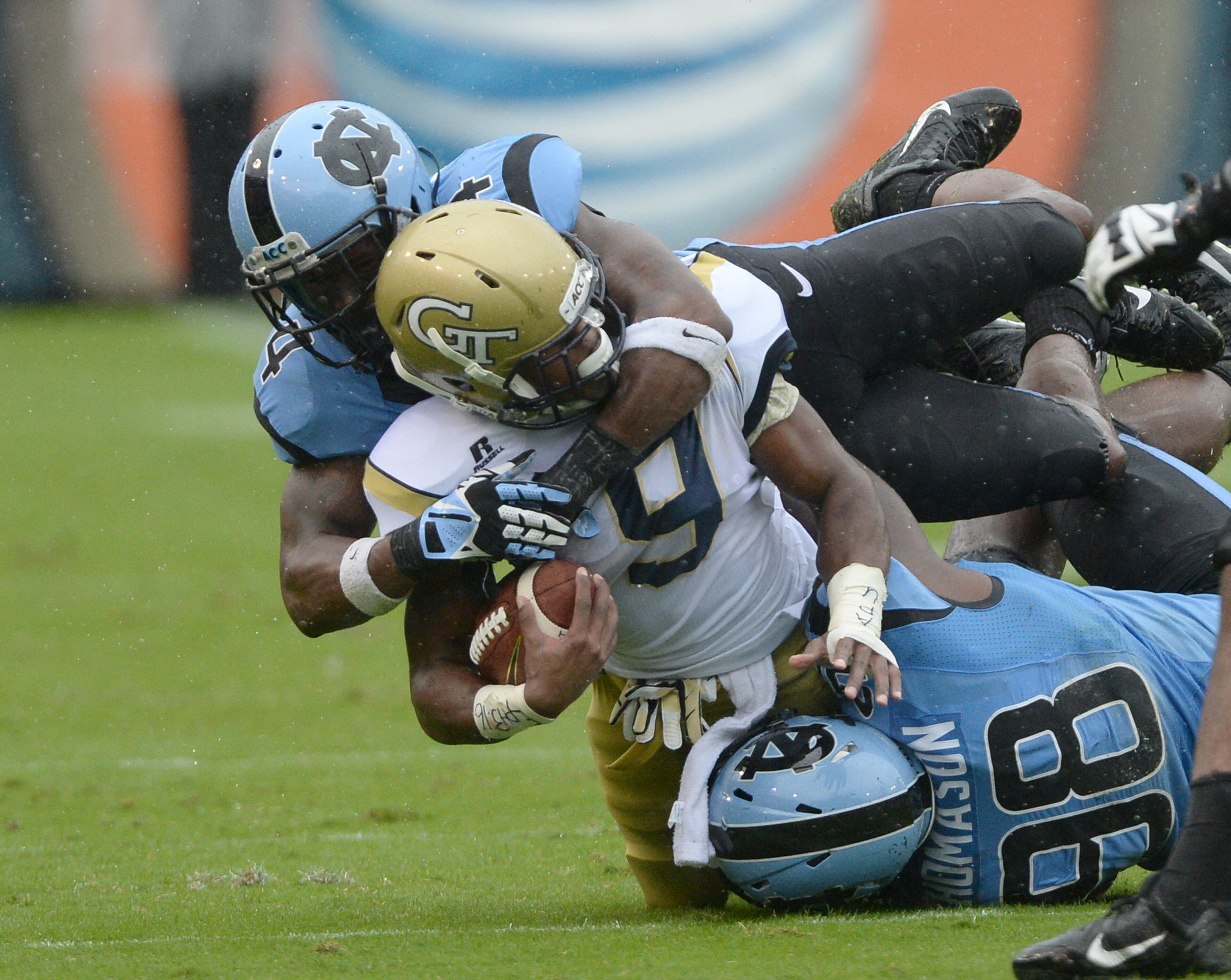 Georgia Tech's Tony Zenon (9) is tackled by North Carolina's Jabari Price (4) and Justin Thomason (98) in Bobby Dodd Stadium on Saturday, September 21, 2013. Tech won the game 28 to 20.
