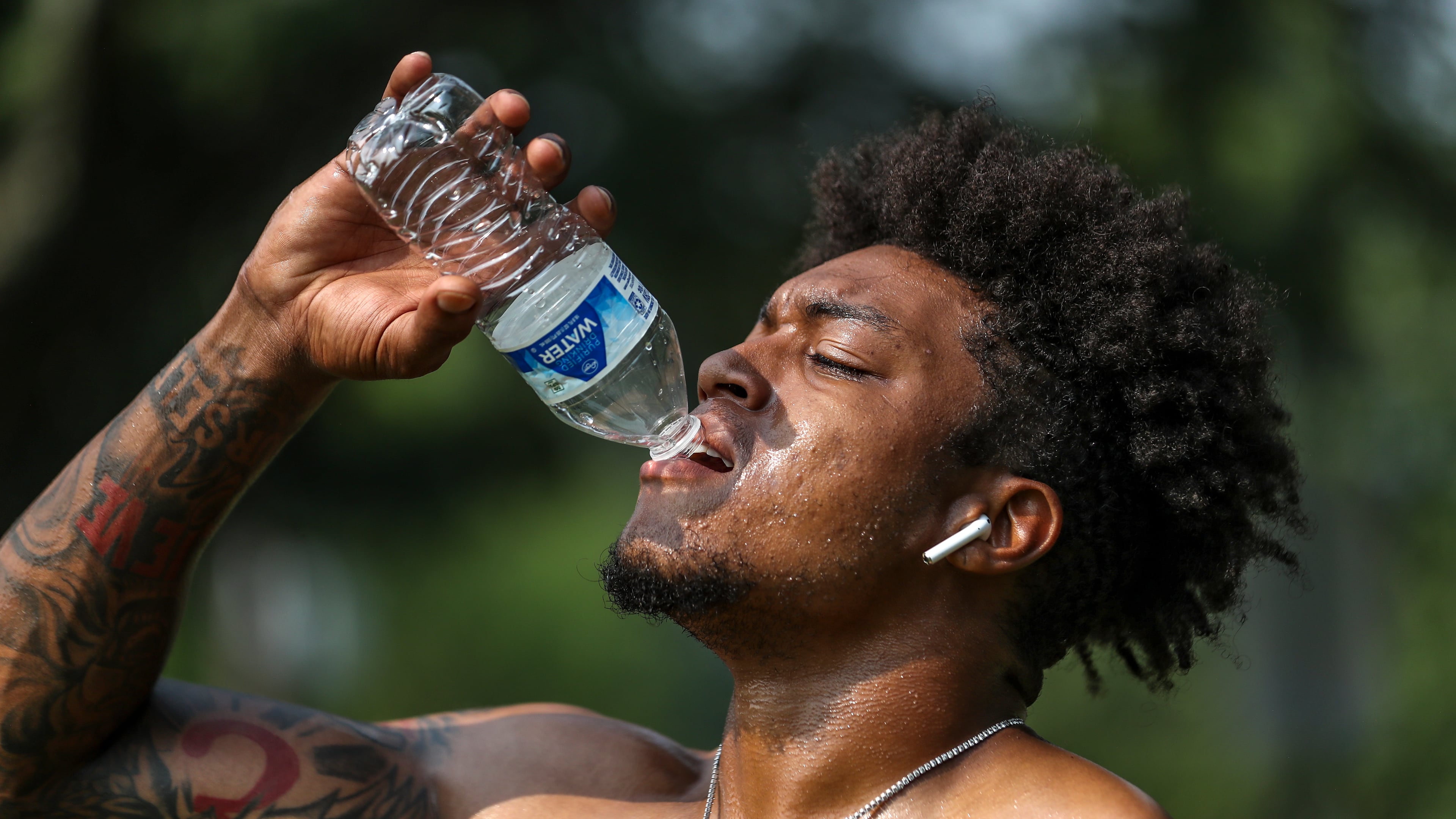 Jacob Jones of Exclusive Training hydrates after working with a client on Tuesday, July 18, 2023, in downtown Atlanta. Although FIFA World Cup matches will be held in the air-conditioned Mercedes-Benz Stadium, most fan events will be outdoors. (John Spink/AJC 2023)