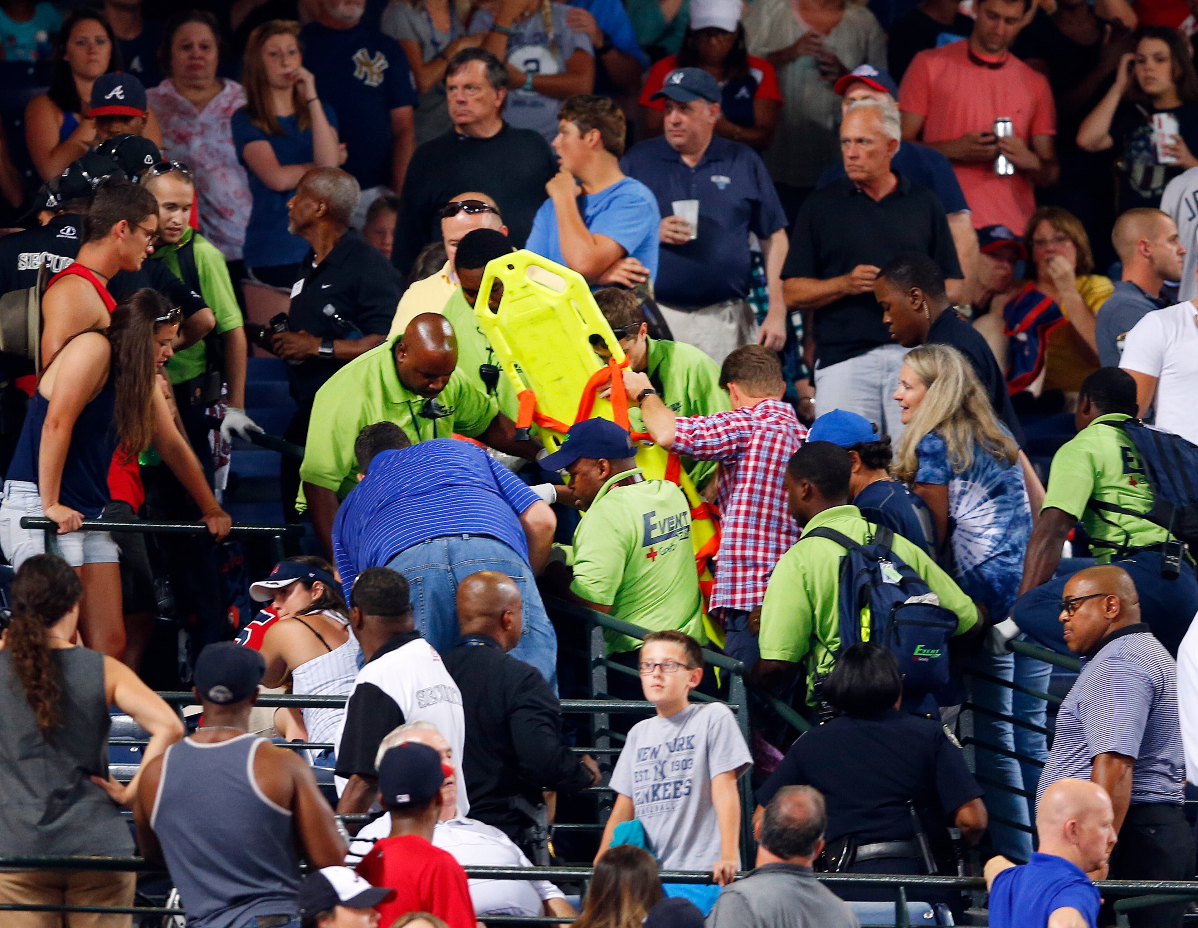 Emergency medical personnel attend to an injured fan in the stands at Turner Field during a baseball game between Atlanta Braves and New York Yankees Saturday, Aug. 29, 2015, in Atlanta. A fan fell from the upper deck into the lower-level stands at Turner Field on Saturday night. (AP Photo/John Bazemore)