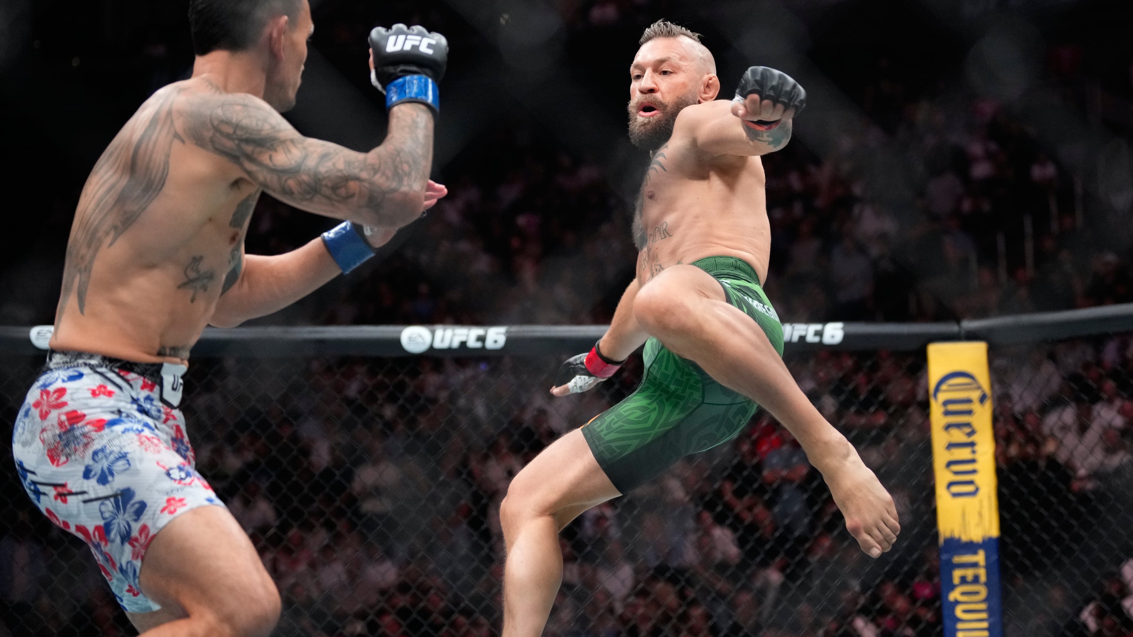 Conor McGregor, right, jumps into the air for a kick as he fights Max Holloway in a welterweight fight at the UFC 329 mixed martial arts event Saturday, July 11, 2026, in Las Vegas. (AP Photo/John Locher)
