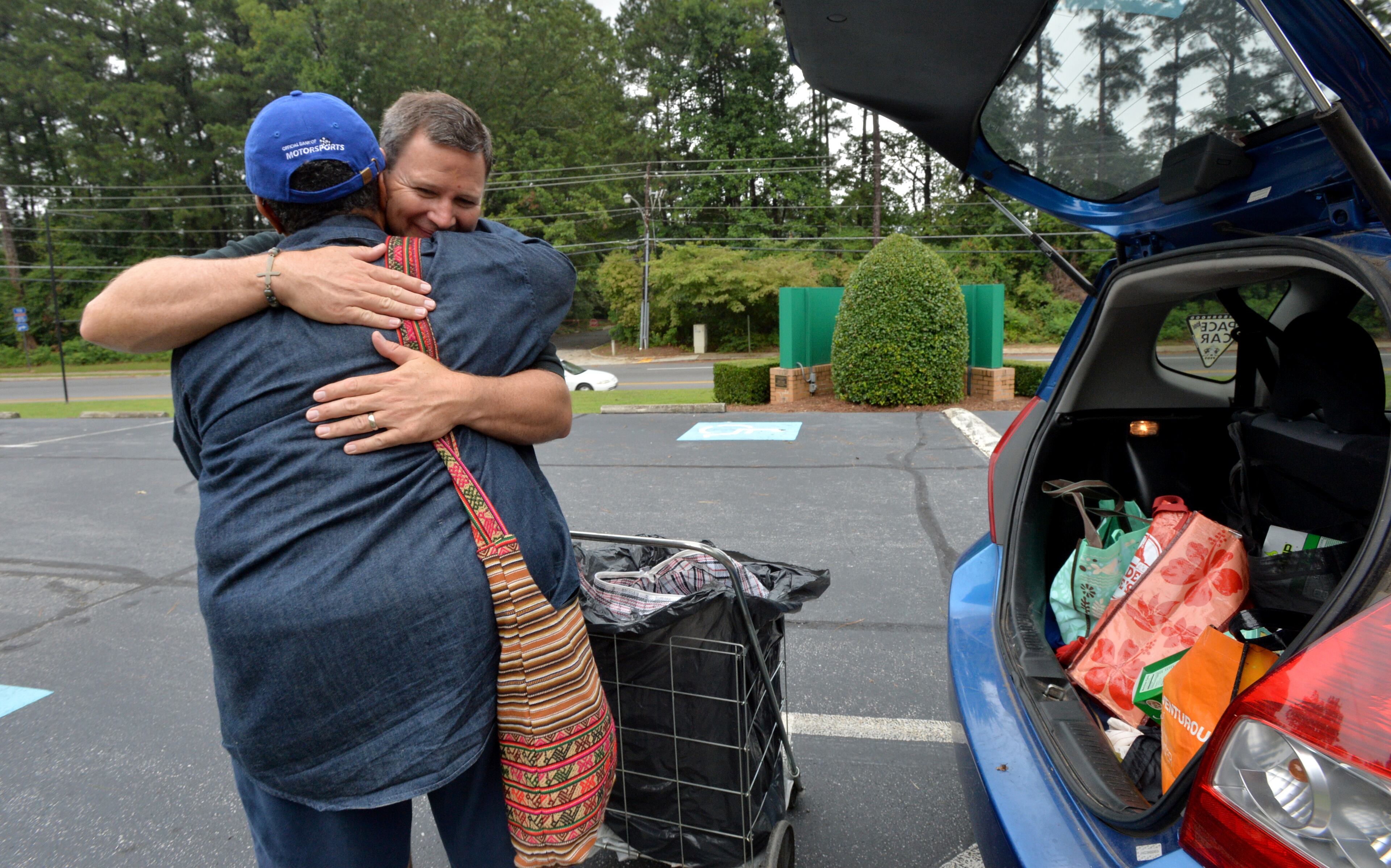 August 9, 2014 Atlanta - Jeremy Turner (behind), executive director of Contribute2America, gets a hug from Freda Lewis after he helped to load the car with foods during C2A Food Co-op's community outreach at Briarcliff United Methodist Church. HYOSUB SHIN / HSHIN@AJC.COM