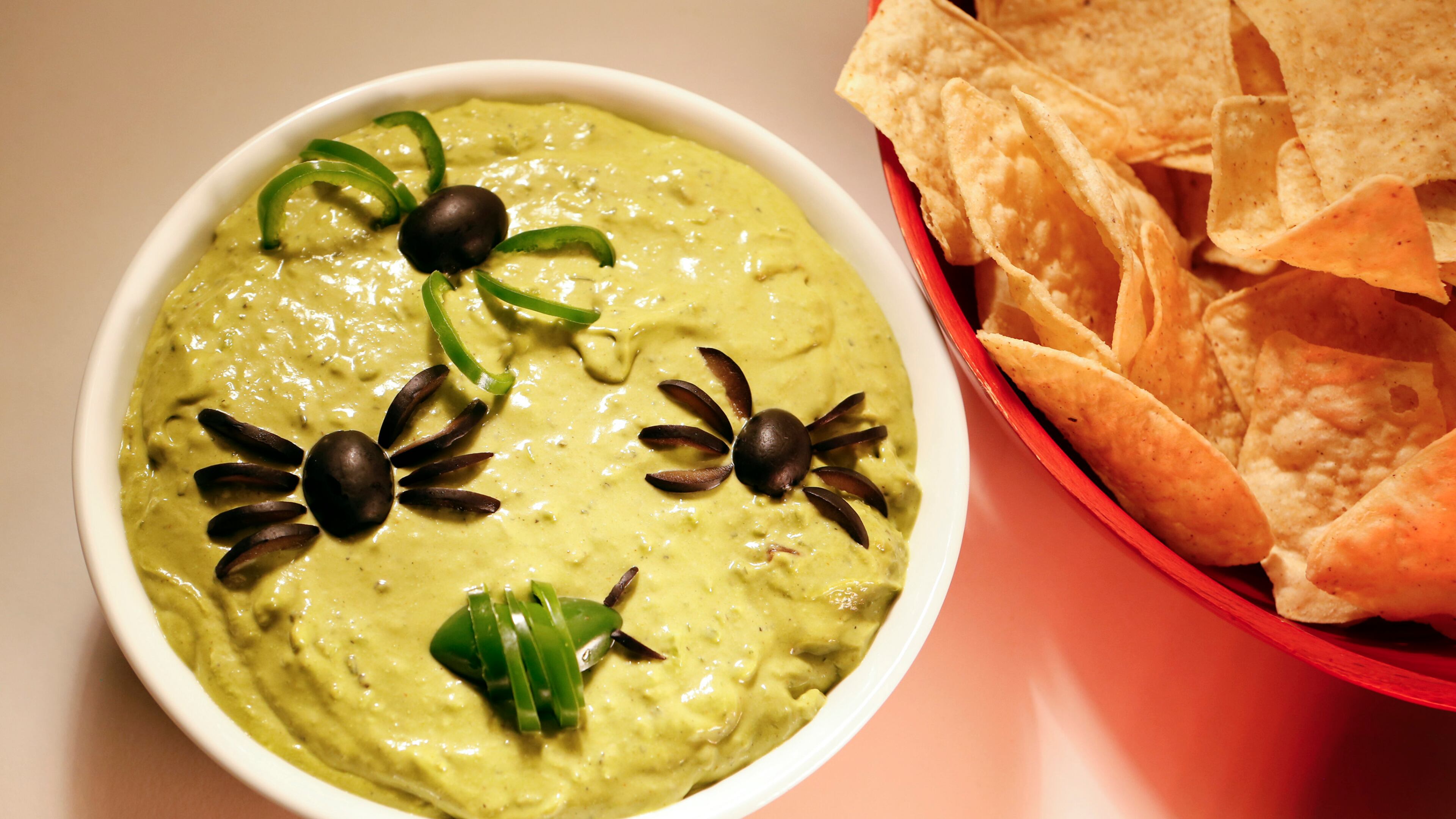 Spread out your guacamole in a large shallow bowl, using cut olives, peppers, onions, cilantro and more to create bugs and other ghoulish decorations. (Anne Cusack/Los Angeles Times/MCT)