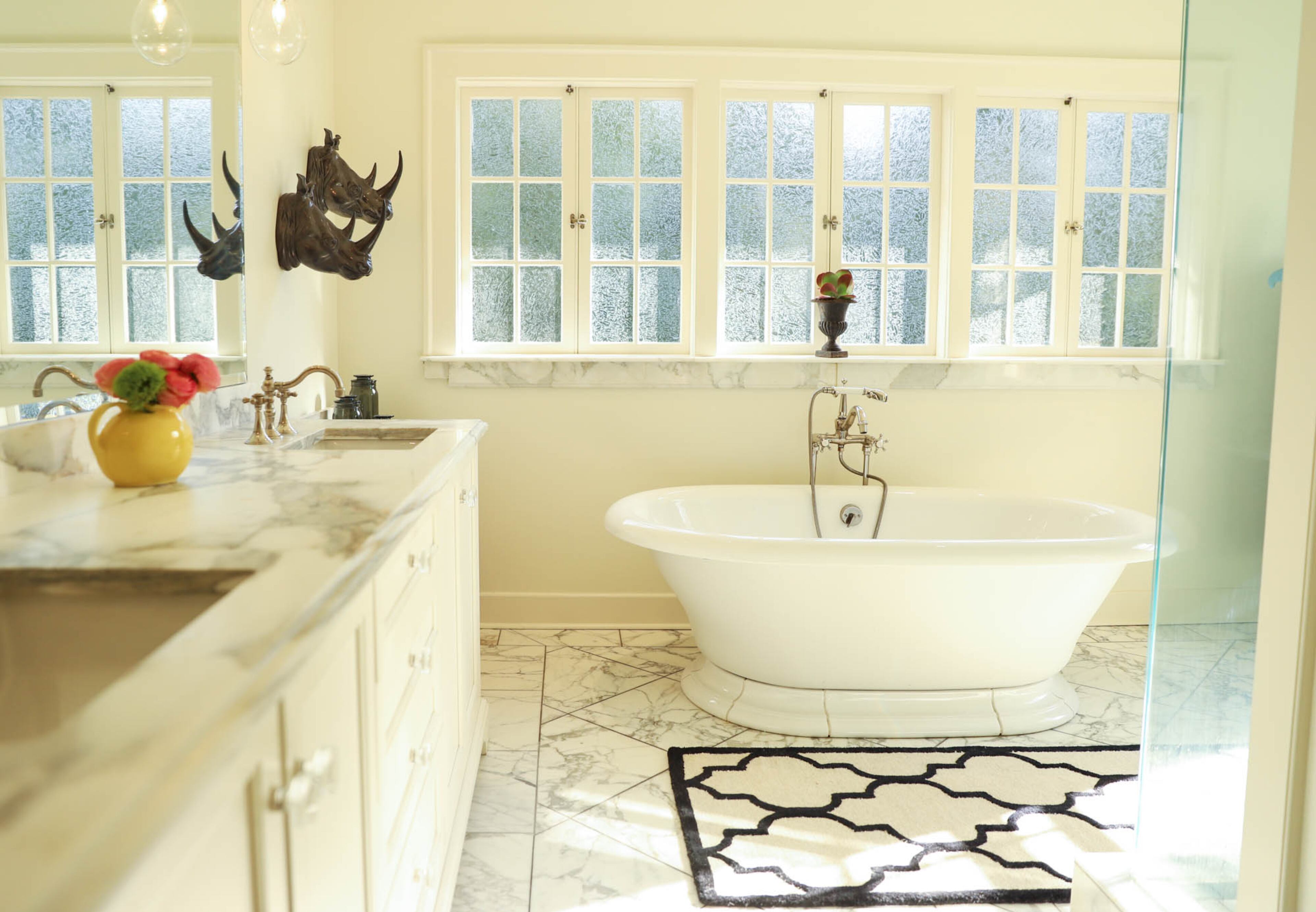 Marble floors and countertops, which are honed, mix with existing windows in the remodeled master bathroom. The soaking tub is from Ferguson.