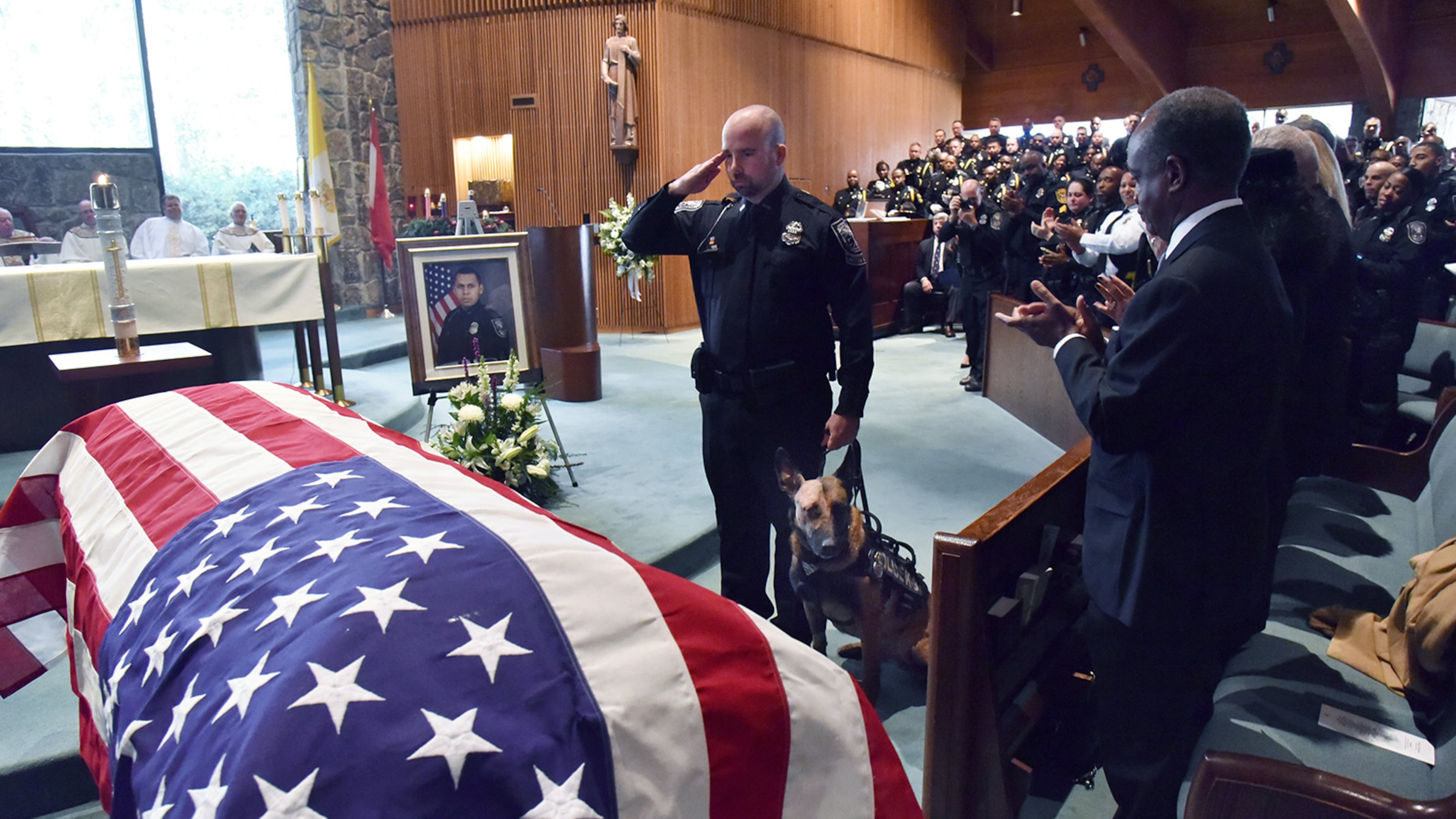December 18, 2018 Dunwoody - K9 Officer Indi, who was shot, is brought to the casket of officer Edgar Isidro Flores during his funeral service at All Saints Catholic Church in Dunwoody on Tuesday, December 18, 2018. Flores was shot and killed in DeKalb County in the line of duty last week. HYOSUB SHIN / HSHIN@AJC.COM
