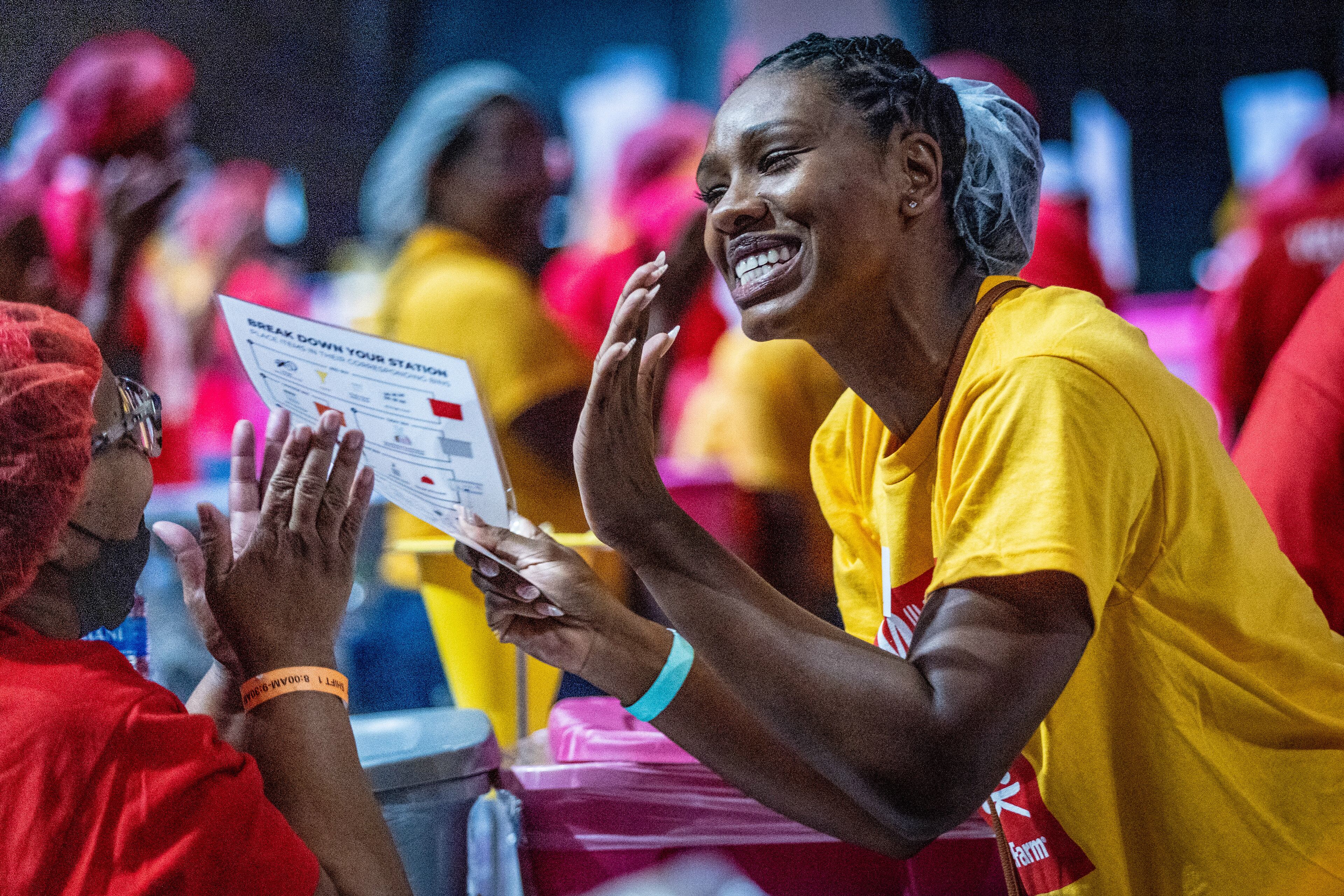 Table Captain Chantel McDonald greets her volunteers as they enter the State Farm Arena during the Million Meal Pack event on Saturday, July 16, 2022. (Steve Schaefer / steve.schaefer@ajc.com)