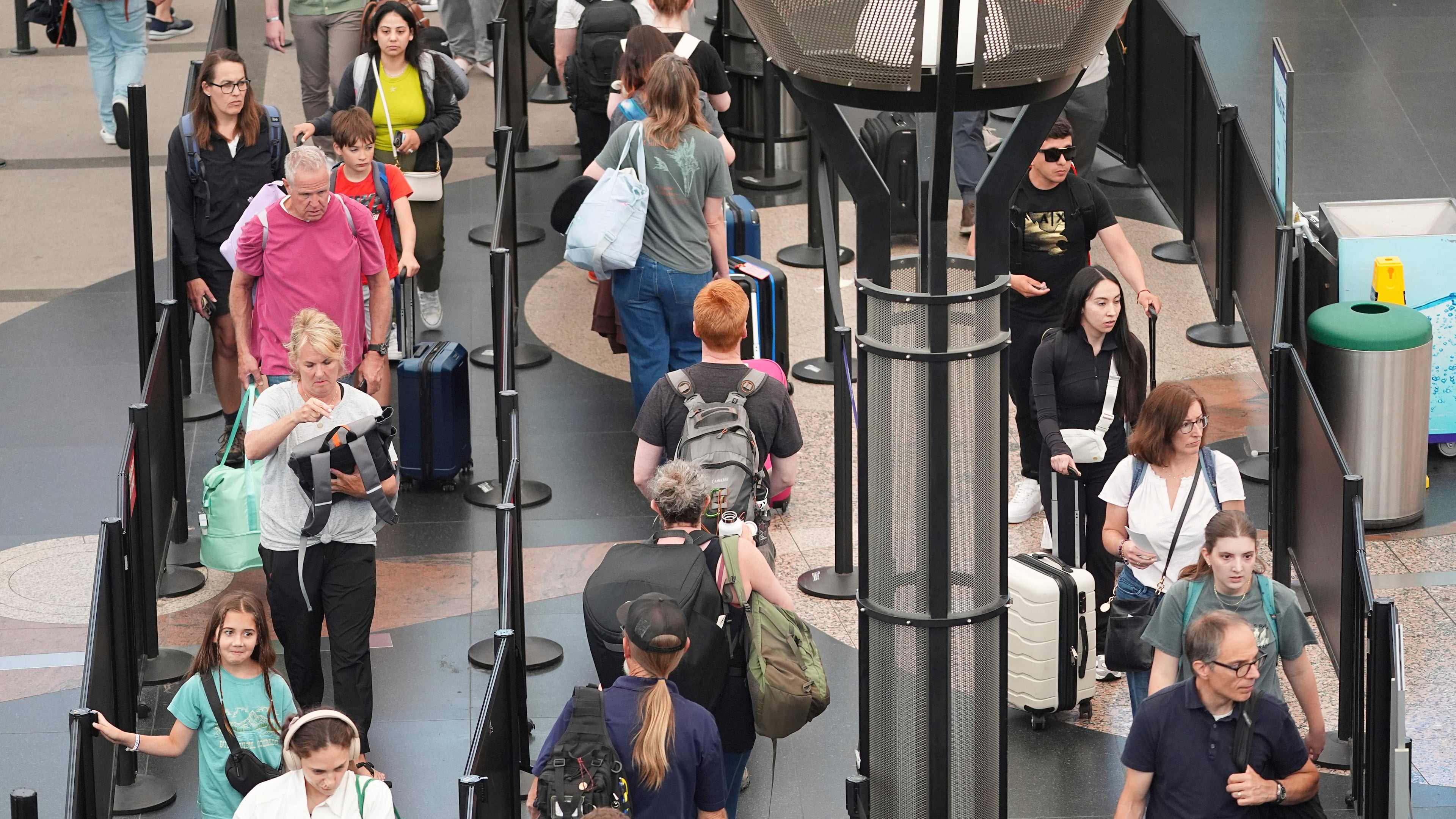 FILE -Travelers queue up to pass through the south security checkpoint in Denver International Airport Wednesday, July 2, 2025, in Denver. (AP Photo/David Zalubowski, File)