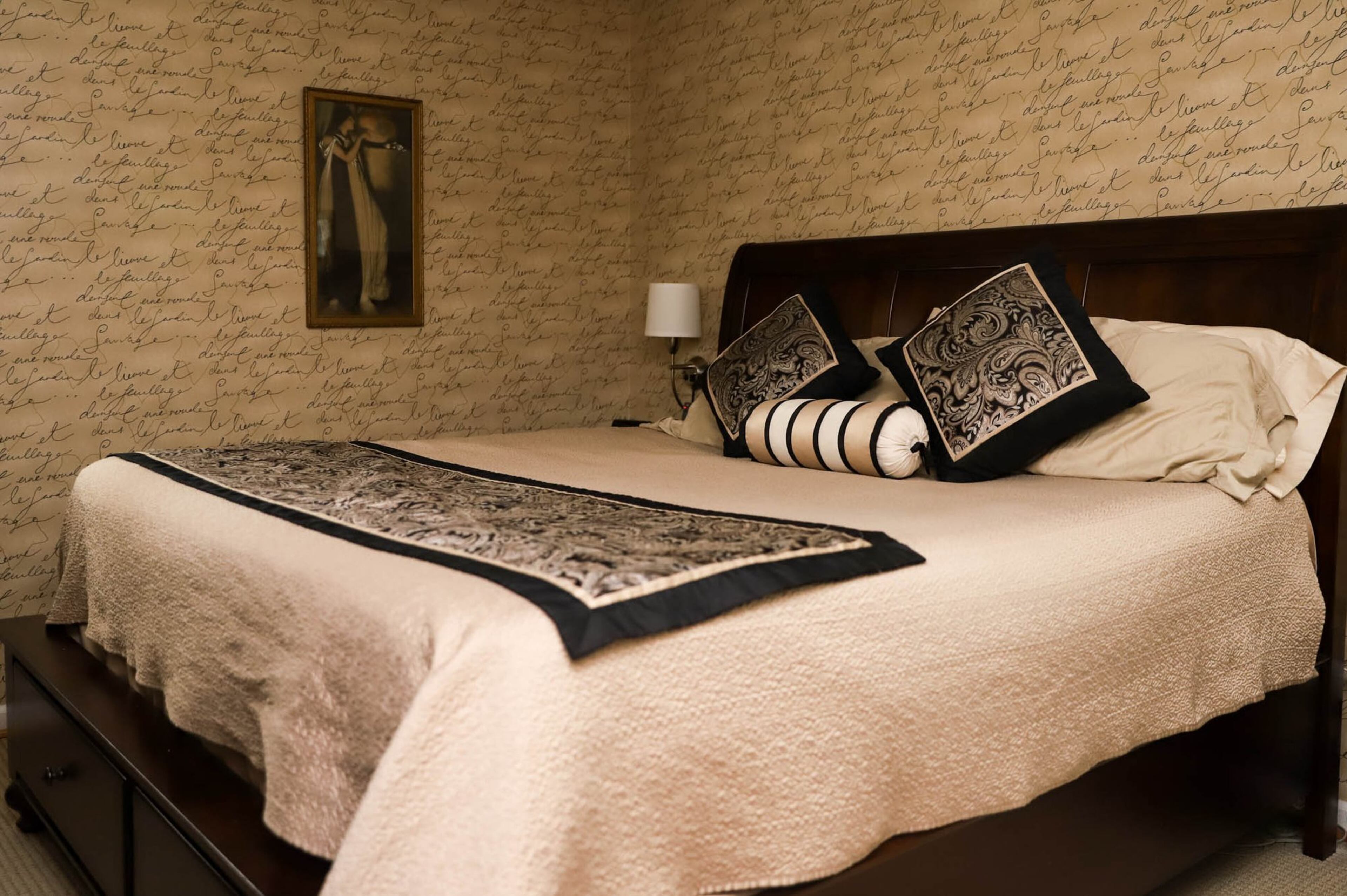 Waverly Gardens wallpaper covered in French writing encases Jeff and Susan Phillips’ master bedroom in a cozy envelope. A bed from Macy’s and bedding from Stein Mart brings the earthy, warm hues from the walls to the bed. Text by Shannon Dominy. Photo by Reynolds Rogers FOR THE AJC.