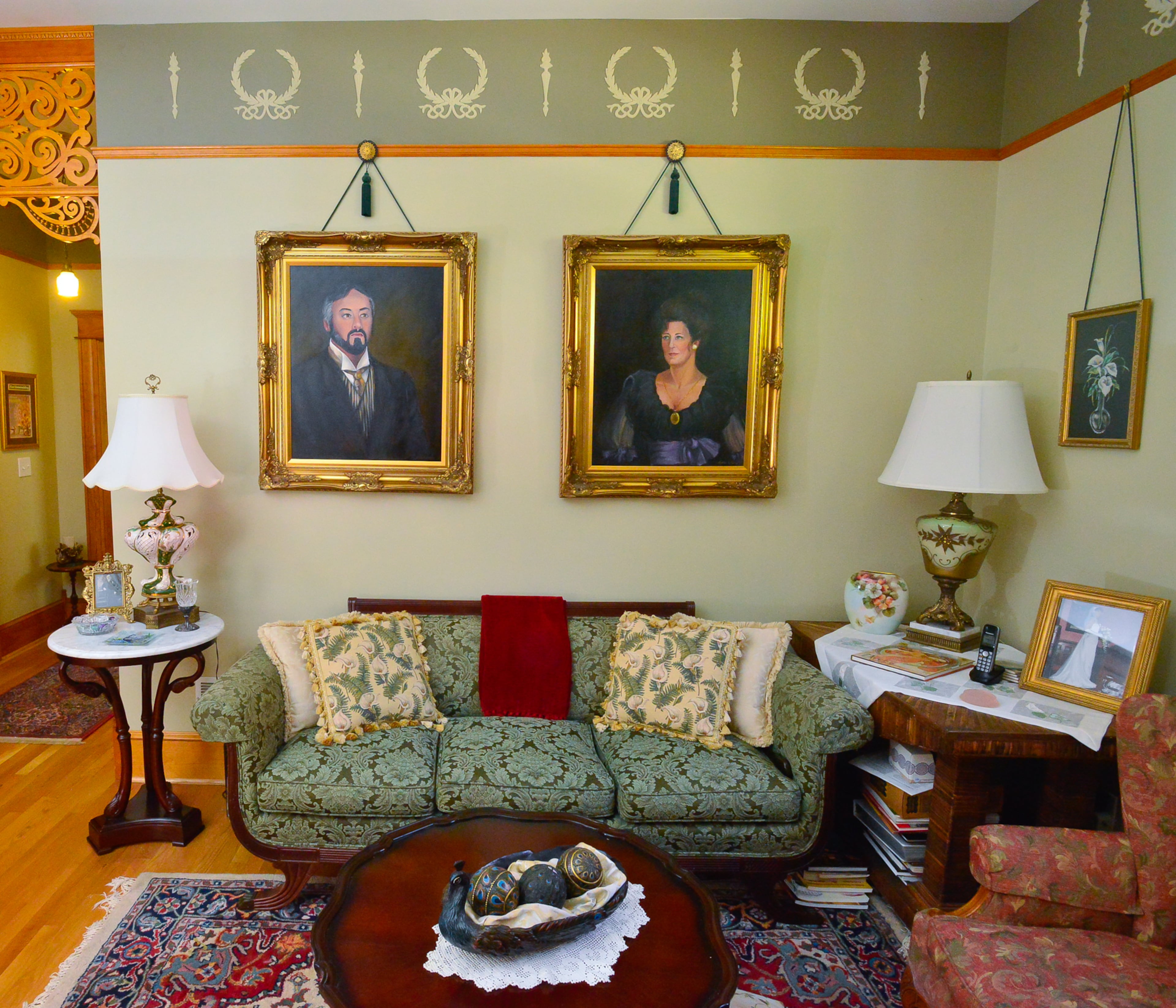 Portraits of homeowners Mike and Carolyn Dufano in Victorian garb have a prominent living room spot over a green upholstered couch that belonged to a friend's grandmother. The plaster ceiling medallion, two spandrels and the frieze was added to the living room in 2008. -- Lori Johnston