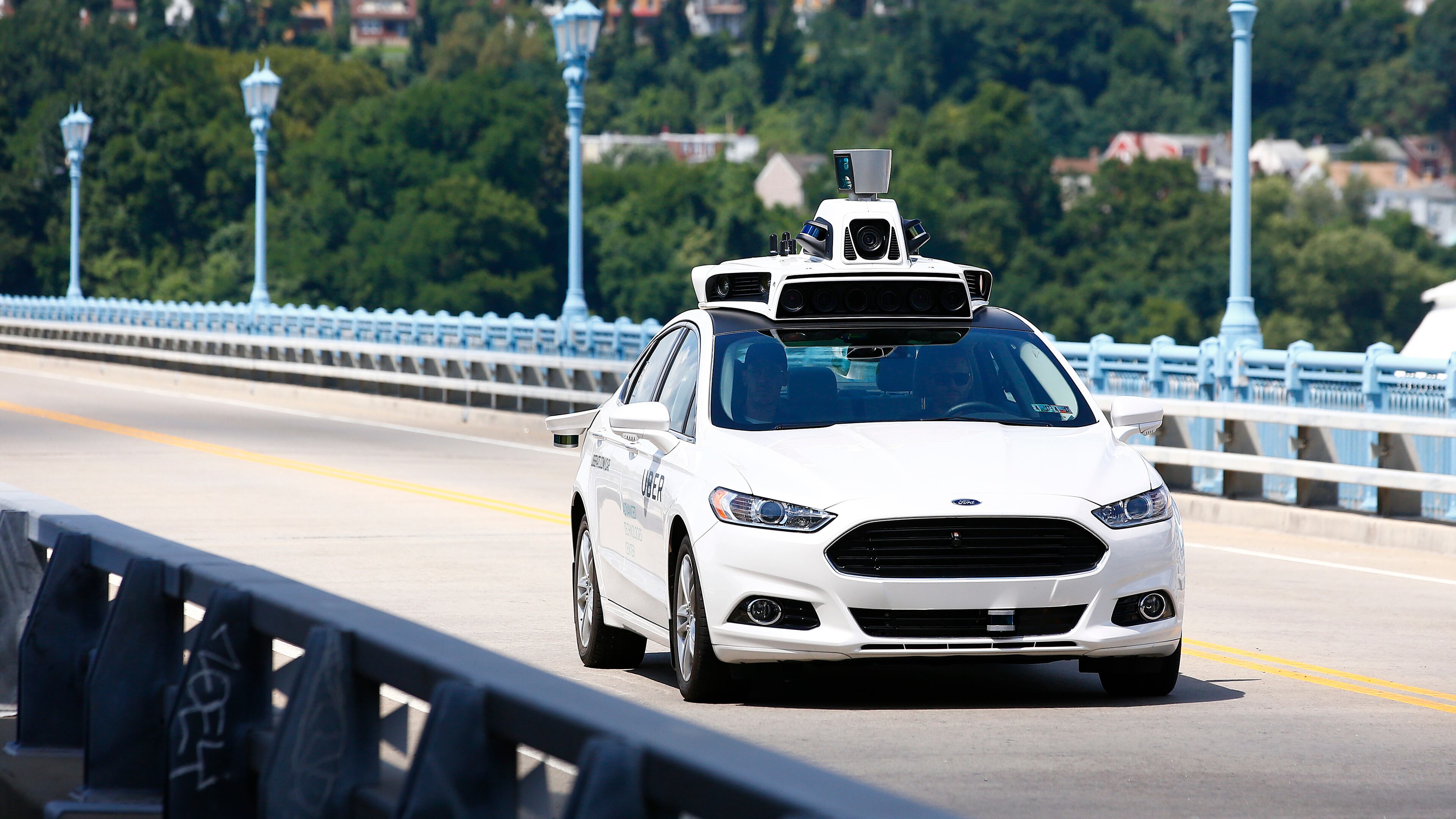 In this Thursday, Aug. 18, 2016, photo, Uber employees test a self-driving Ford Fusion hybrid car, in Pittsburgh.