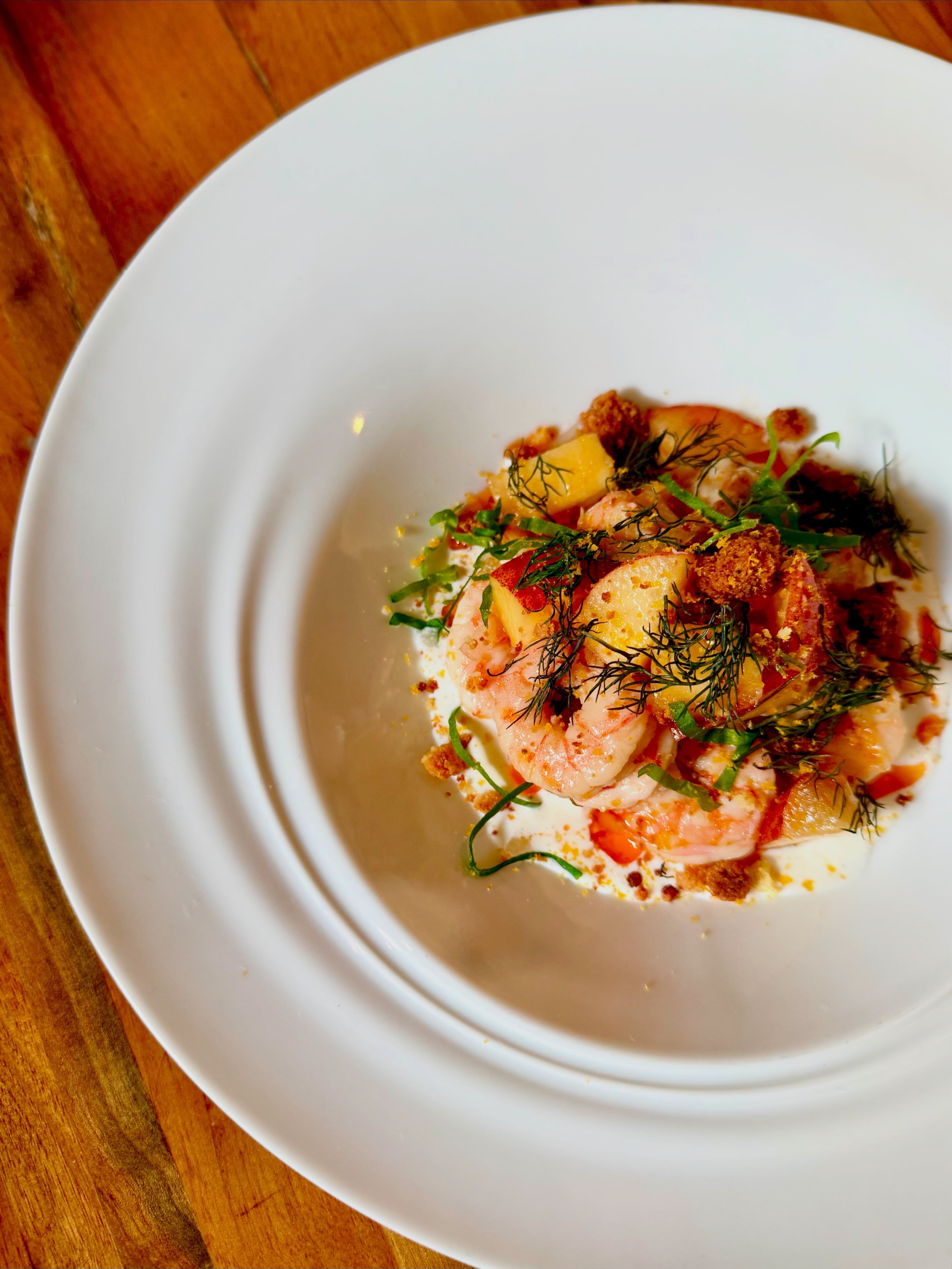 Sweet peaches and shrimp are served with buttermilk dressing, bottarga, fresh herbs and cornbread crumbles at Staplehouse. (Angela Hansberger for the AJC)