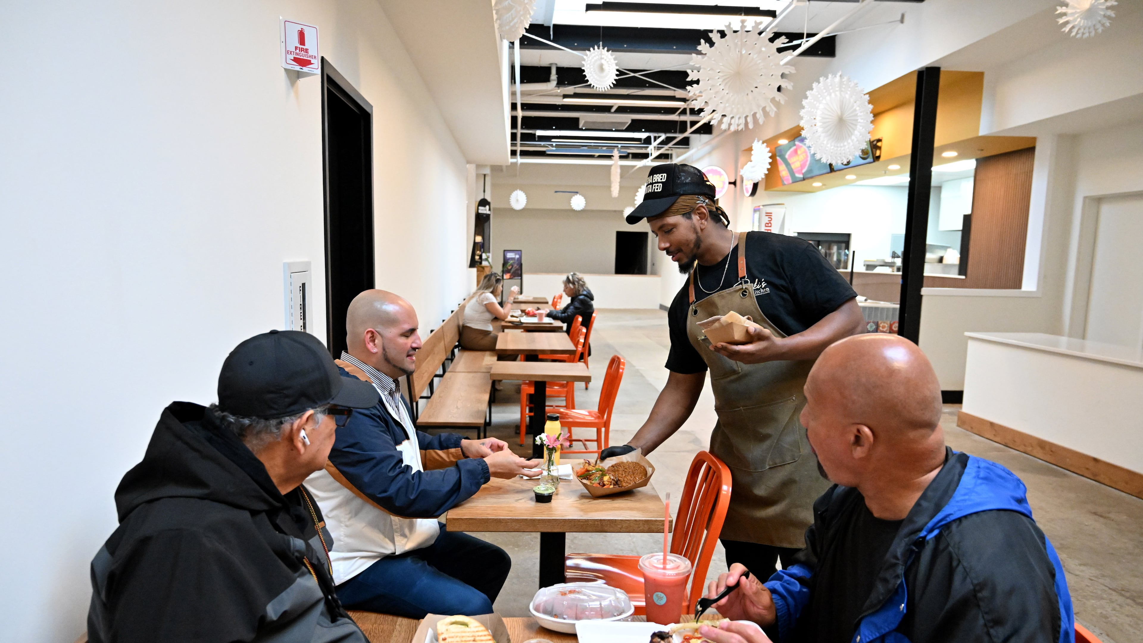 Ali Lemma (standing), owner and chef at Ruki’s Kitchen, serves food at Terminal South, Thursday, Feb. 26, 2026, in Atlanta. This is Lemma's first year participating in Atlanta's Black Restaurant Week. (Hyosub Shin/AJC)