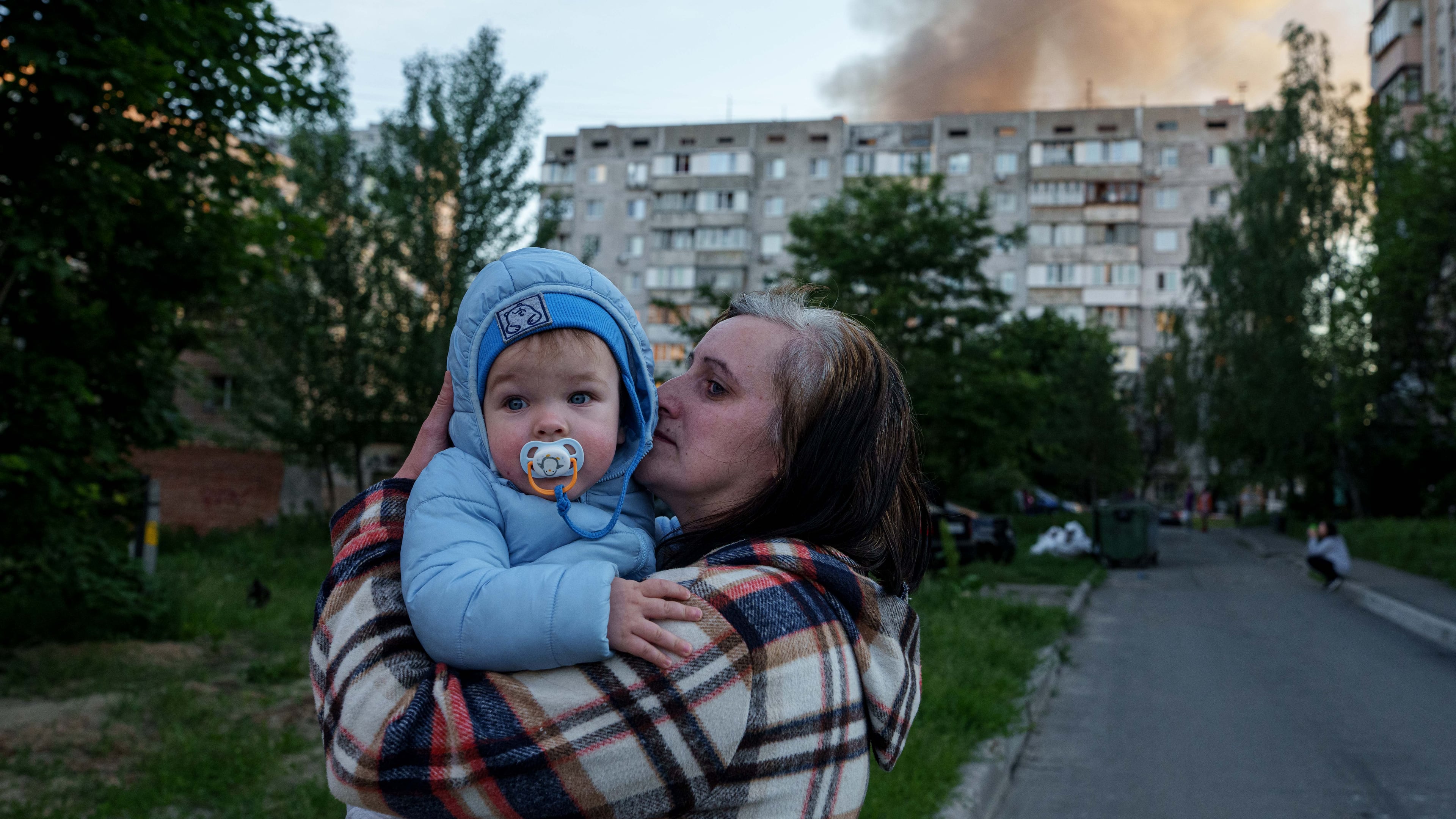 A woman carries a baby near a residential house damaged after a Russian strike in Kyiv, Ukraine, on Tuesday, June 2, 2026. (AP Photo/Evgeniy Maloletka)