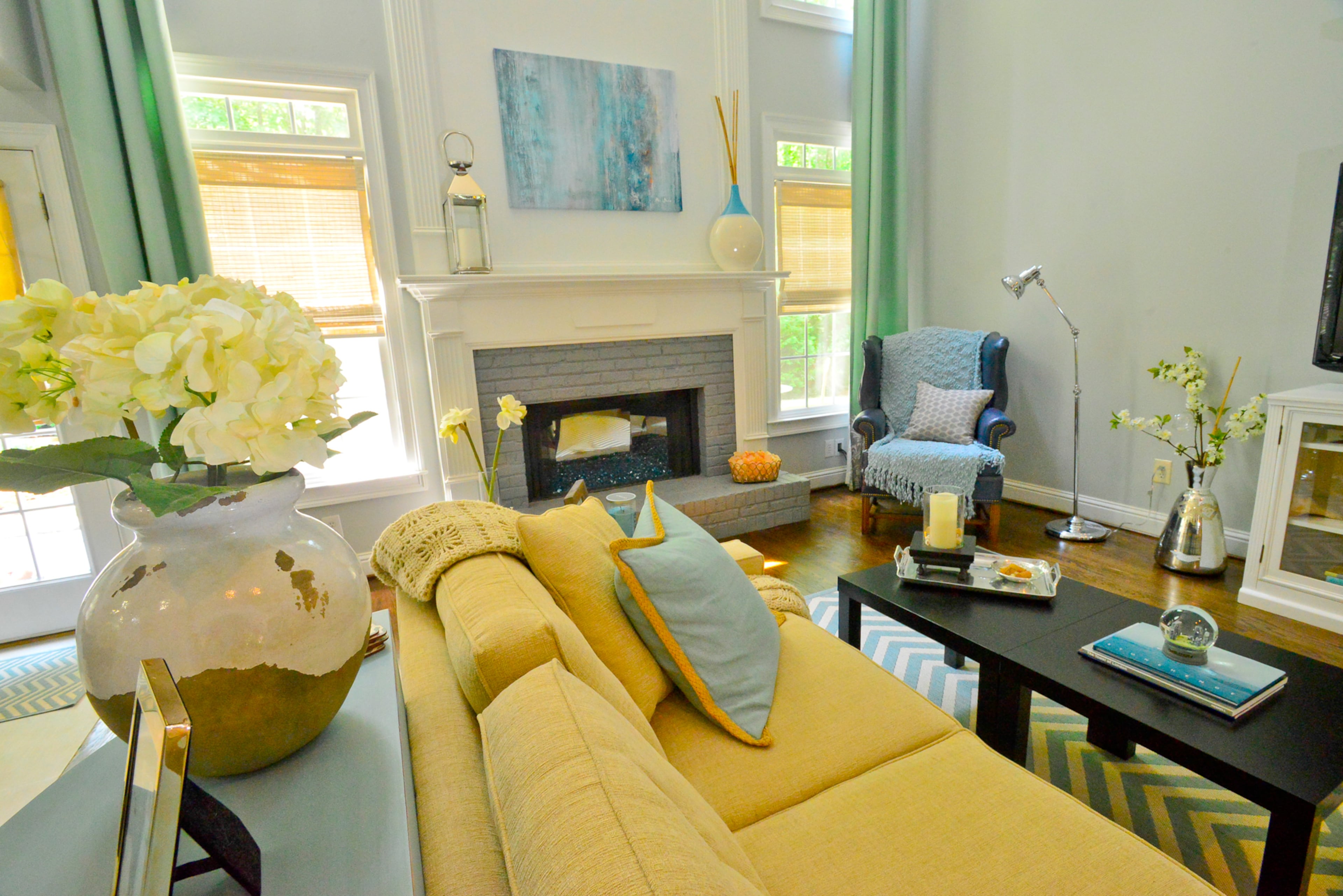 Originally the fireplace was a red brick, but they painted the brick a blue gray (Behr Premium Plus in Pewter Mug) to better match the room's color palette and Pensive Sky walls (Behr Premium Plus). The homeowners also changed out the wood-burning fireplace with a custom mirror backdrop and blue fireglass for a more contemporary look.