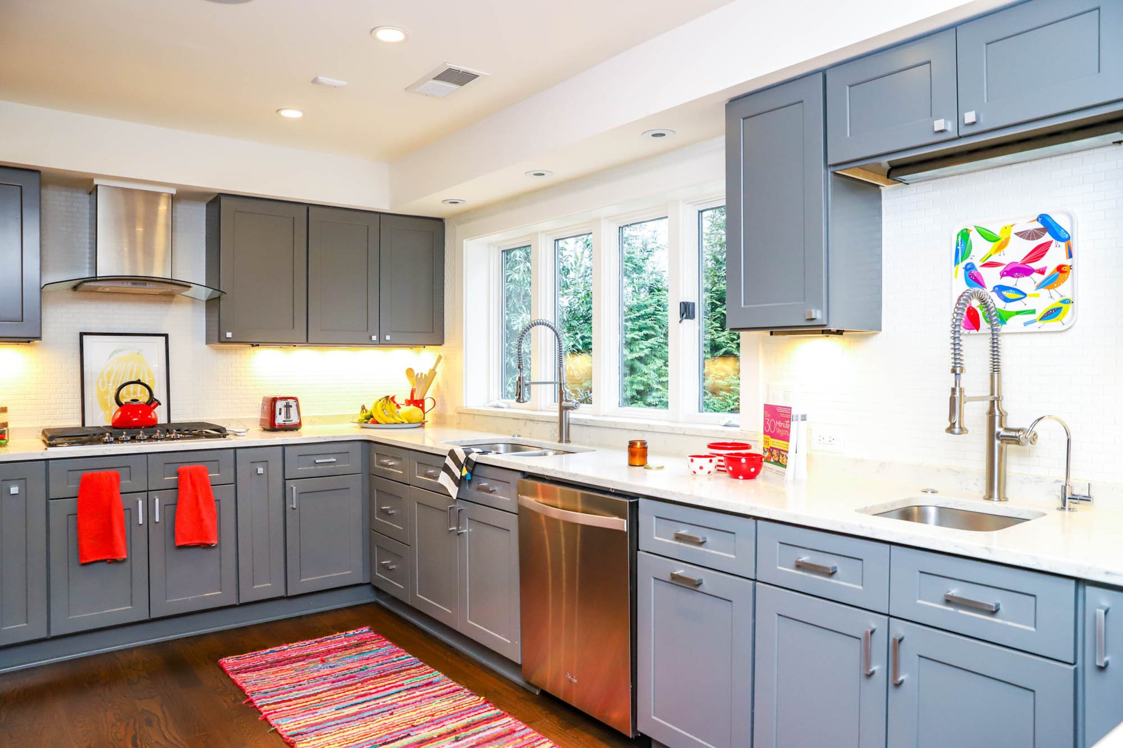 The kitchen of Paola and Jeff Roder’s Johns Creek home is large and open, with muted gray cabinets and a large window that lets in a lot of natural light. Paola loves that the space is open, without an island to block the flow of the room. Text by Shannon Dominy. Photo by Reynolds Rogers.