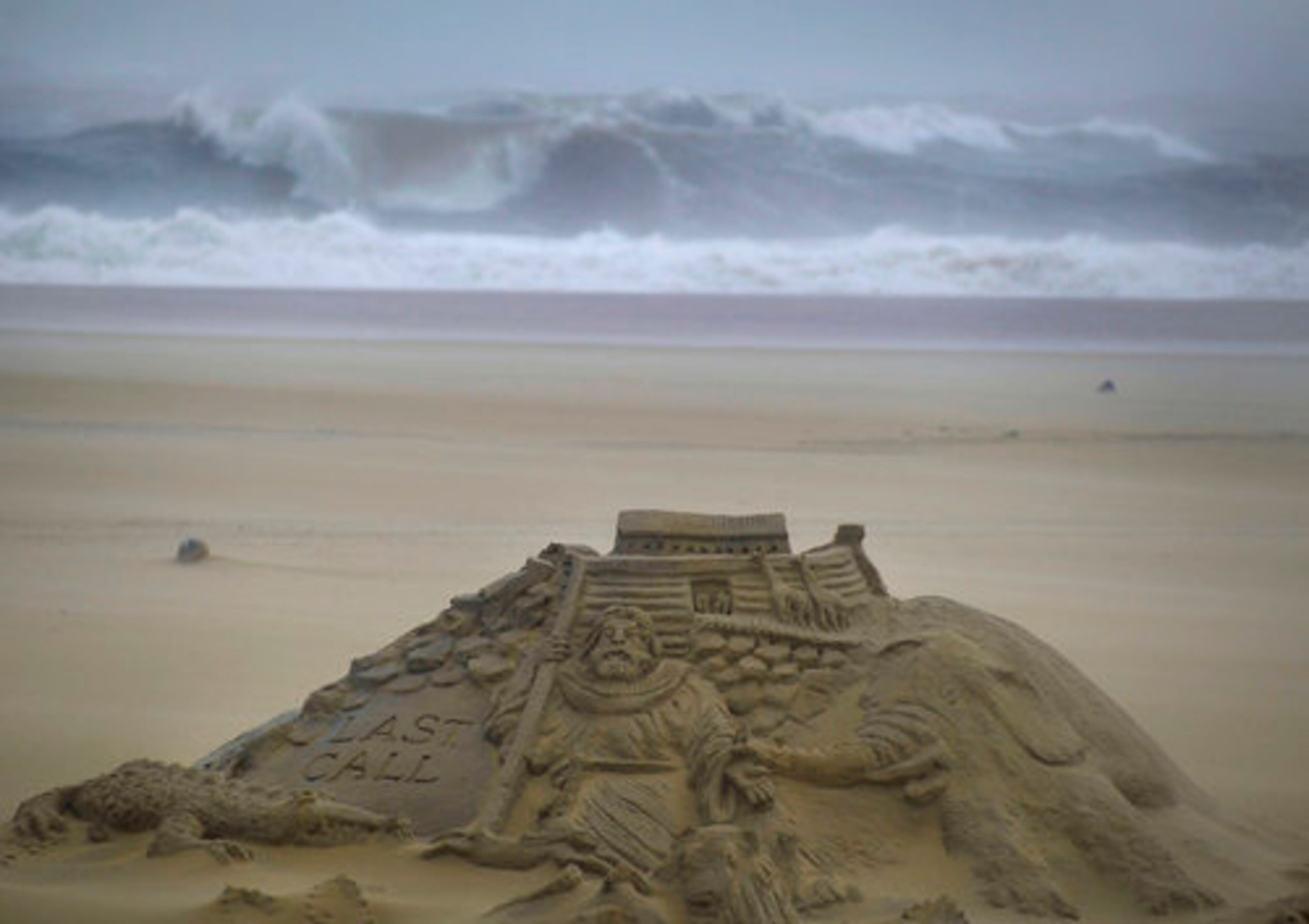 Waves of the Atlantic Ocean churn on the shore behind an artist's rendering of Noah's Ark, created in a sand sculpture, as rain and winds preceding the full impact of Hurricane Irene in Ocean City, Maryland, Saturday, August 27, 2011.