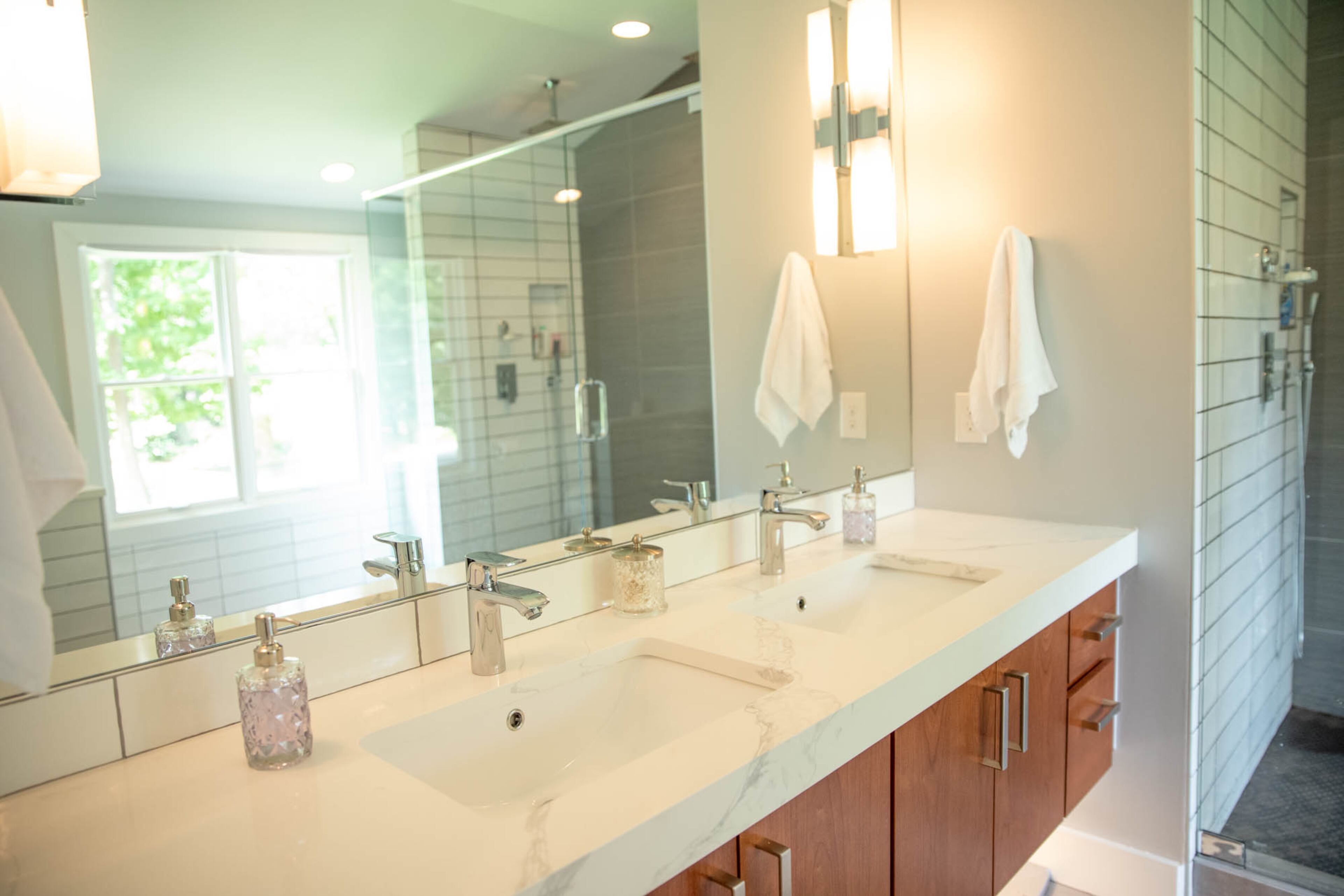 The cedar of the floating vanity in Adam Perry and Ben Ratossa's master bath matches the planks on their bedroom ceiling, giving the master suite a cohesive flow. When the couple renovated their second floor earlier this year they worked with architect Allyson McCarthy of Truco McCarthy and builder Jessica Murphy of Her Cave Atlanta to raise the roof and make the space more functional for the couple, both of whom are tall. This included enlarging the shower, which is now 8 feet long.