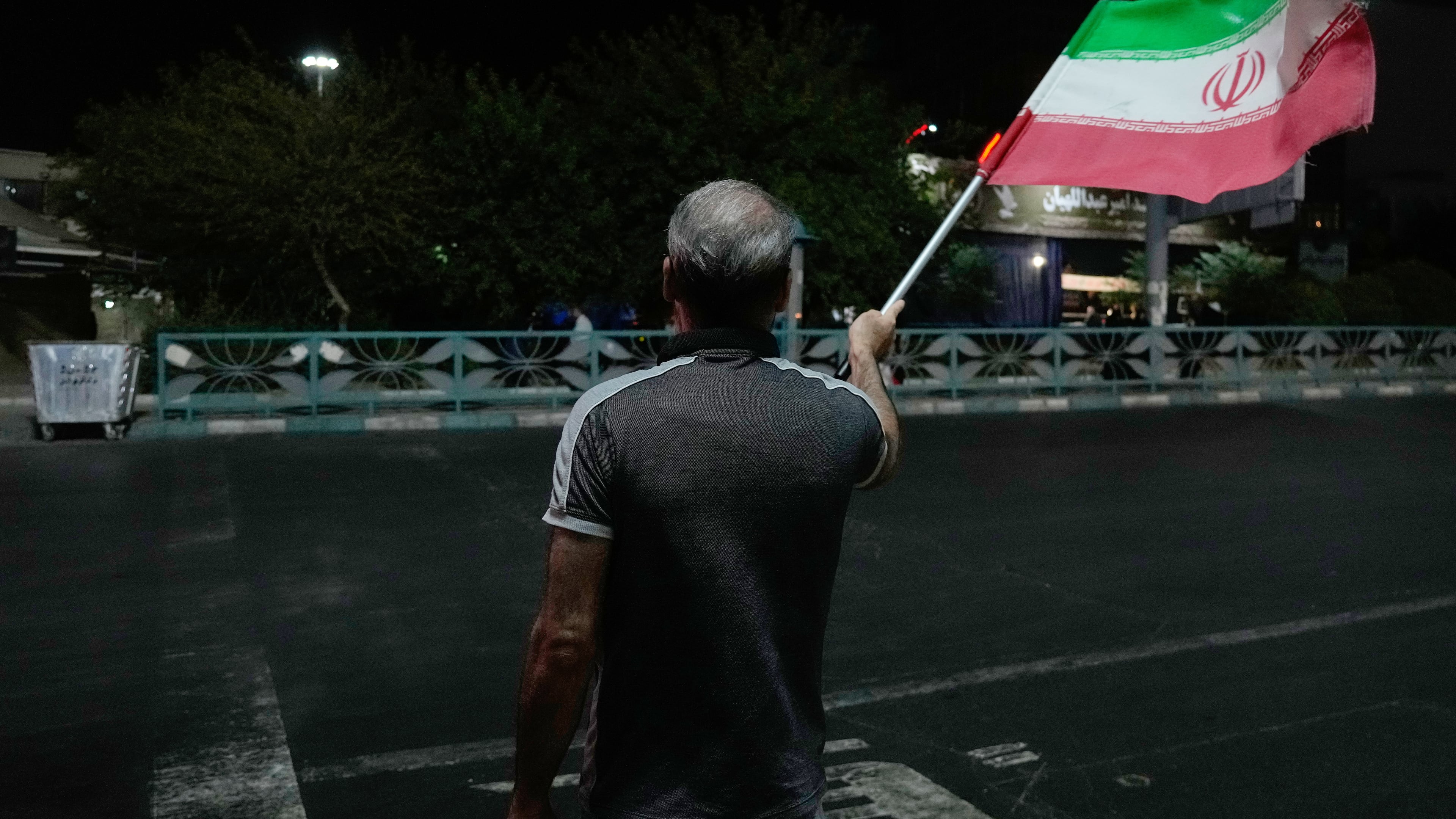 A pro-government demonstrator waves an Iranian flag in a gathering commemorating the late Iranian Supreme Leader Ayatollah Ali Khamenei at a square in Tehran, Iran, Saturday, July 11, 2026. (AP Photo/Vahid Salemi)