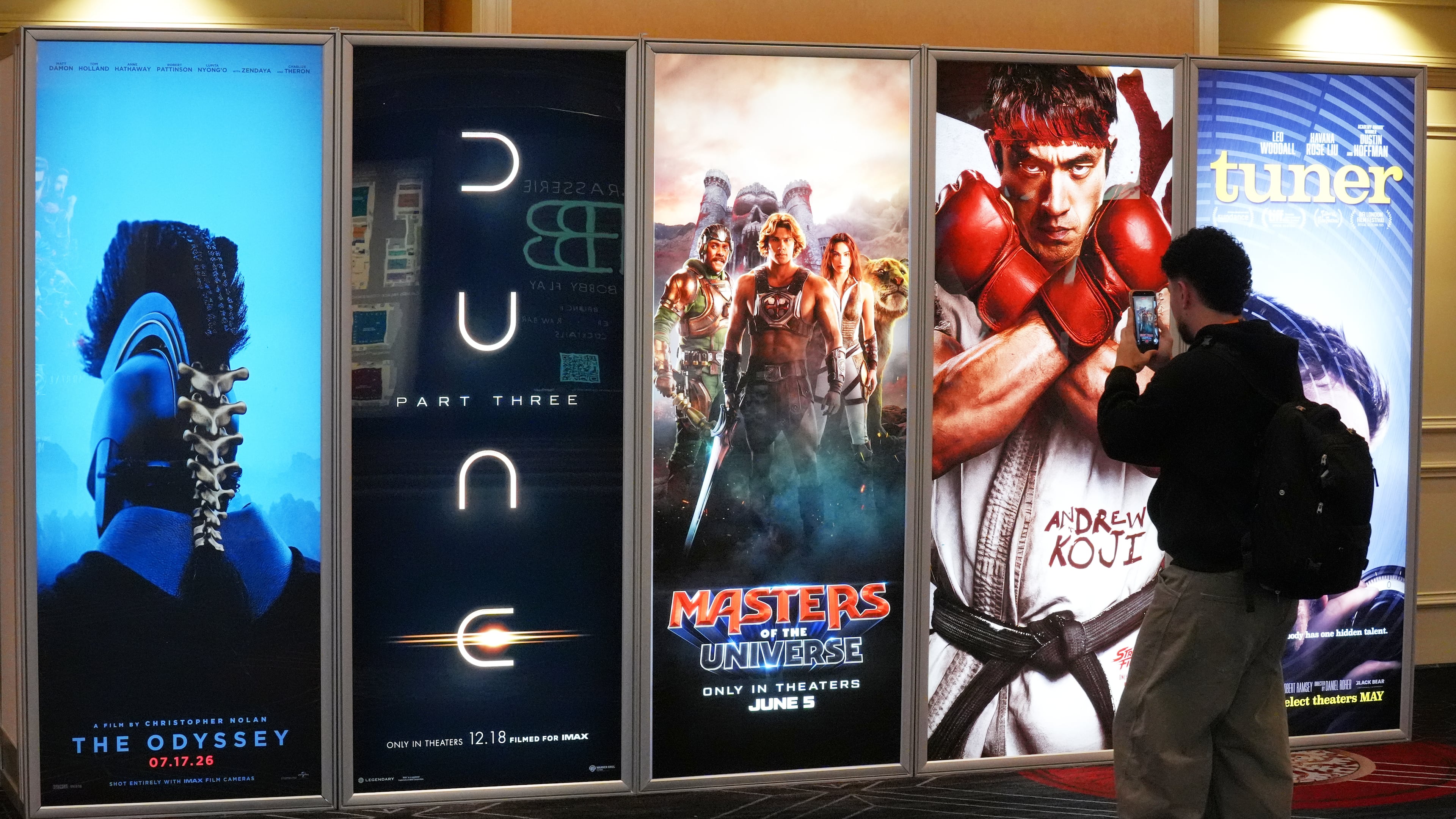 A CinemaCon attendee takes a picture of advertisements for upcoming films during the opening day of CinemaCon 2026, the official convention of Cinema United, on Monday, April 13, 2026, at Caesars Palace in Las Vegas. (AP Photo/Chris Pizzello)