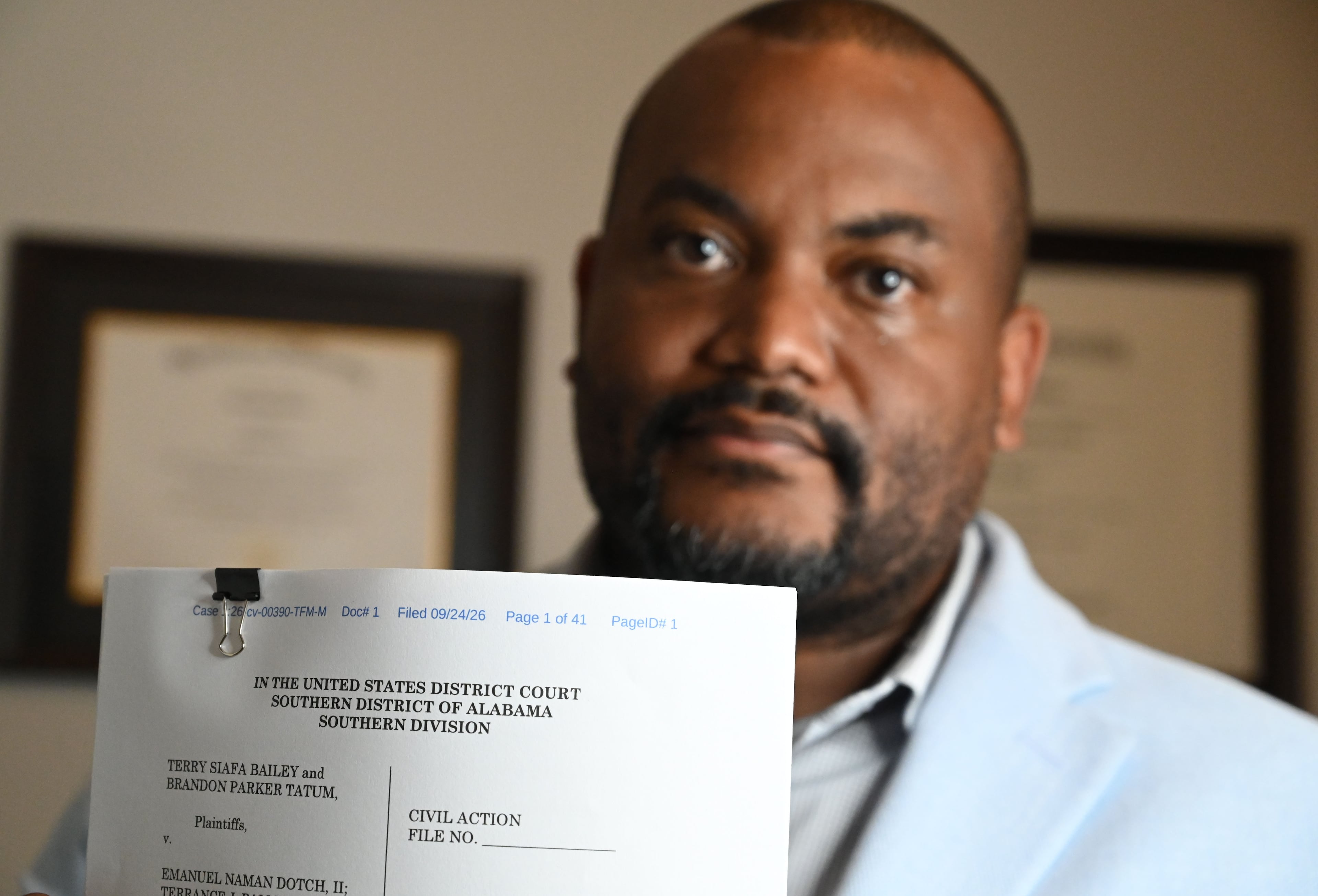 Atlanta attorney Terry Bailey holds a copy of a lawsuit he and his driver filed in Alabama after their arrest there in November. (Hyosub Shin/AJC)