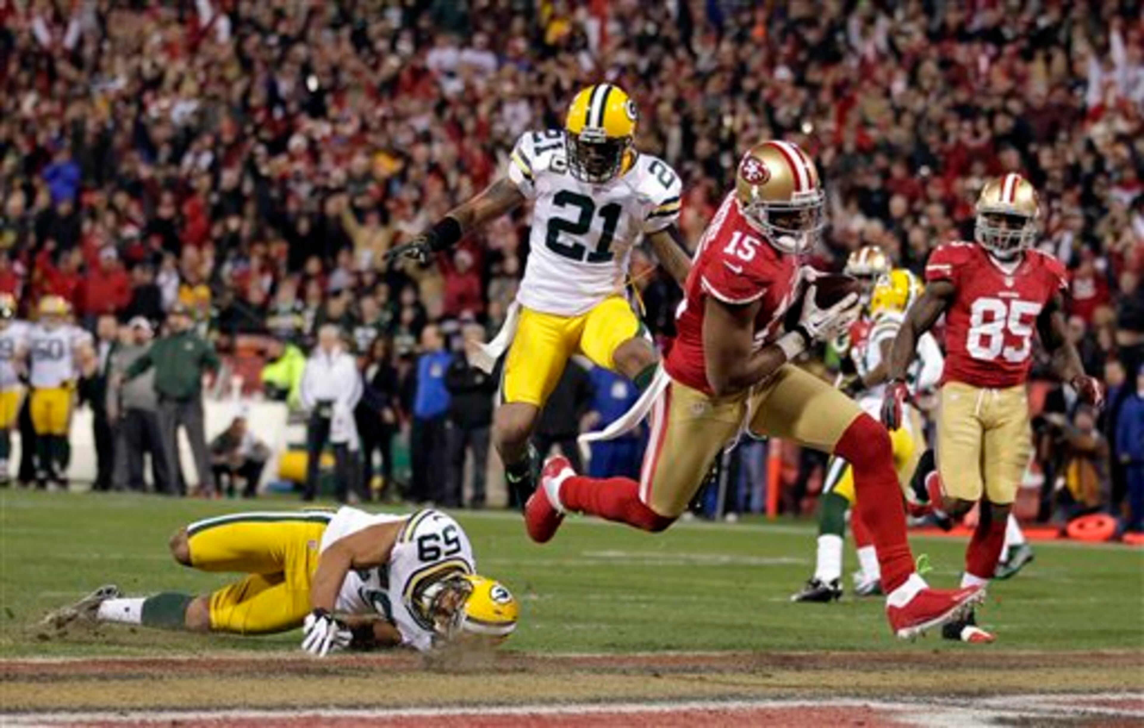 San Francisco 49ers wide receiver Michael Crabtree (15) scores a touchdown as Green Bay Packers inside linebacker Brad Jones (59), and strong safety Charles Woodson (21) move in to stop him in the first half of an NFC divisional playoff NFL football game in San Francisco, Saturday, Jan. 12, 2013. (AP Photo/Tony Avelar)