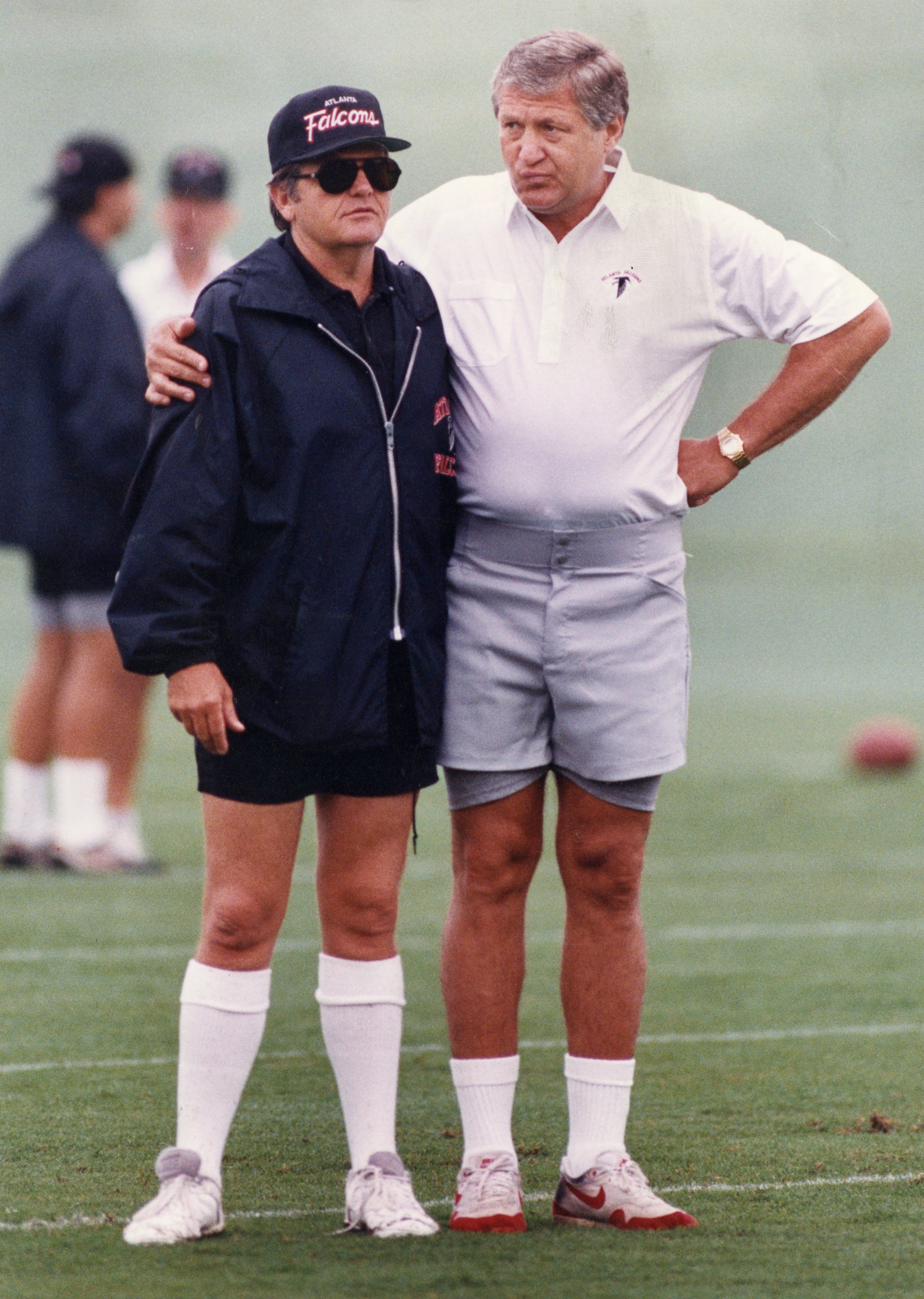 Glanville (left) gets a hug from team executive Ken Herock during training camp in 1991. AJC file photo