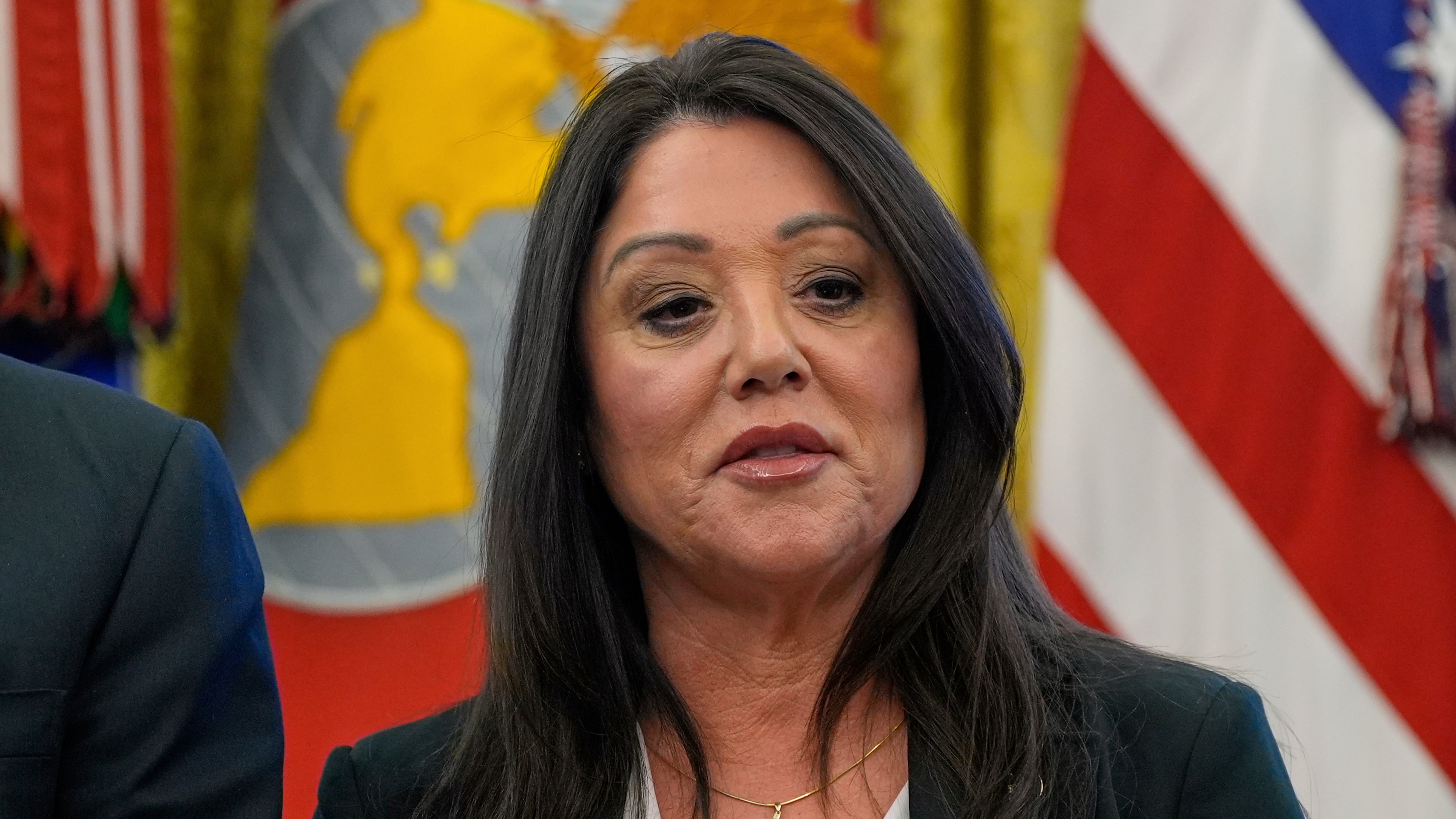 FILE - Labor Secretary Lori Chavez-DeRemer listens as President Donald Trump speaks with reporters while signing executive orders in the Oval Office of the White House, April 23, 2025, in Washington. (AP Photo/Alex Brandon, File)