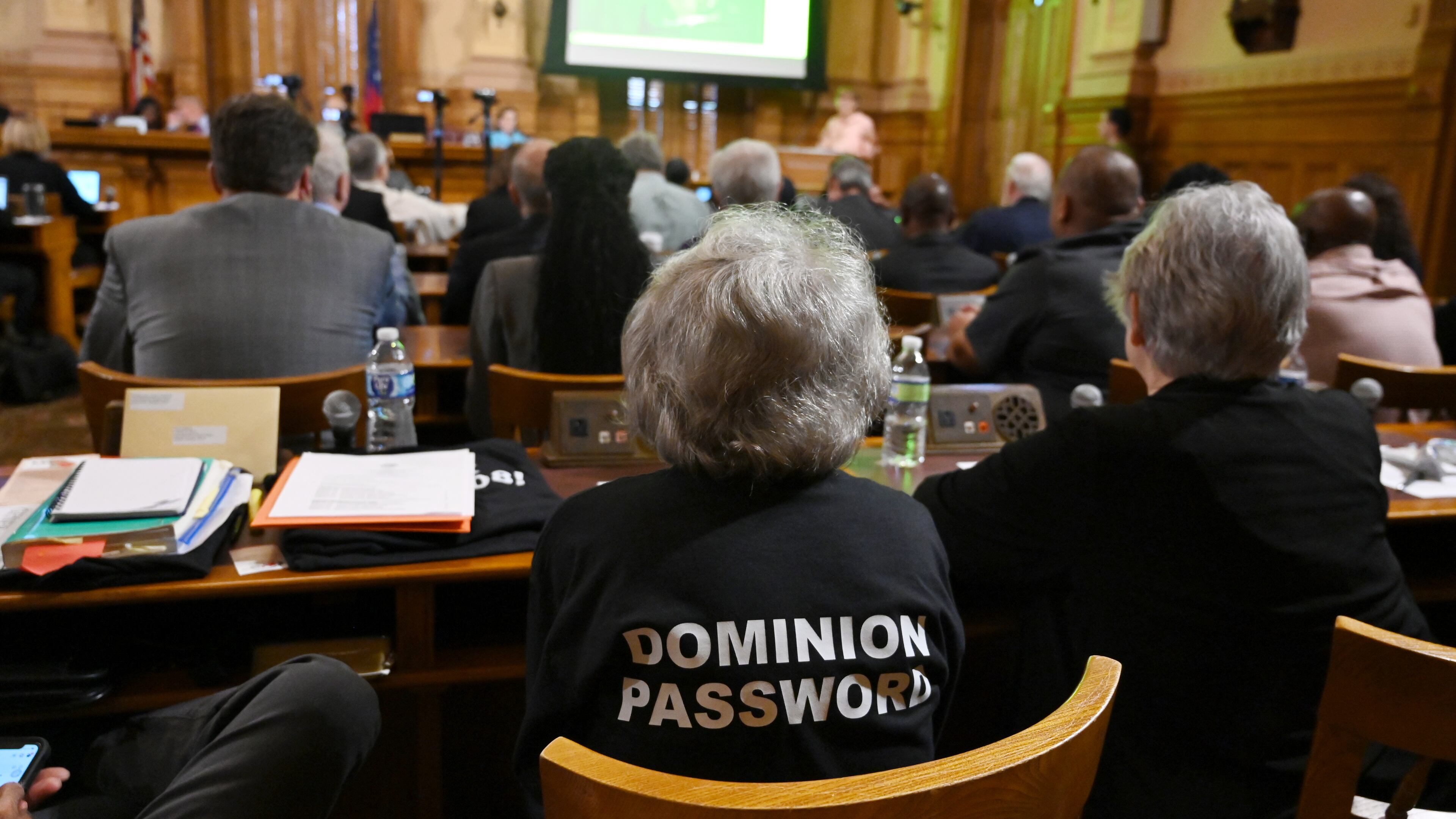 A member of the audience wears a “Dominion Password” T-shirt earlier this month at the State Election Board’s final scheduled meeting of 2024. The state's Dominion Voting System machines are among the things voters cite to explain their distrust in Georgia's election system. (Hyosub Shin/AJC)