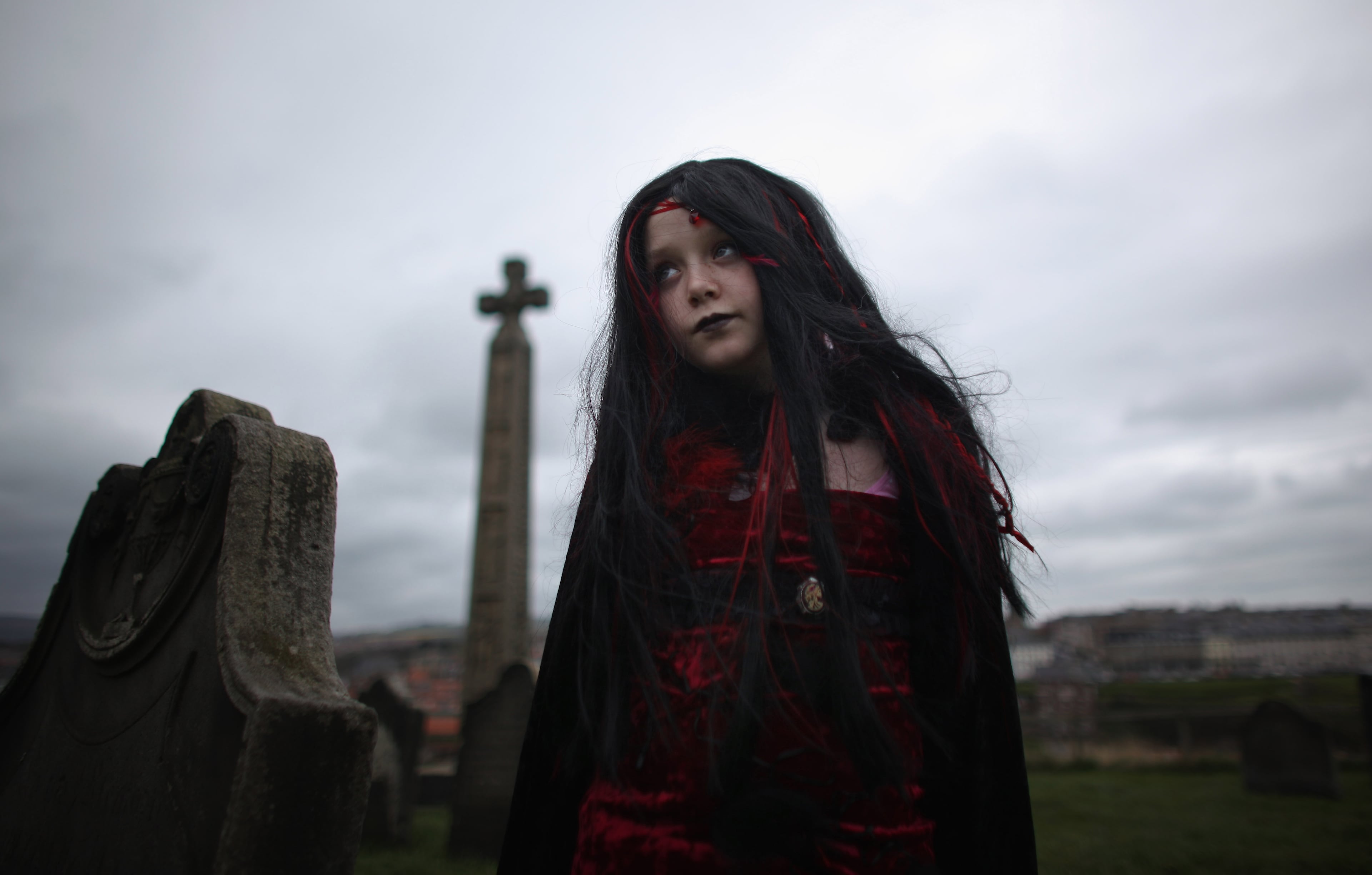 WHITBY, ENGLAND - APRIL 28: A young goth poses near gravestones during the Whitby Goth Weekend on April 28, 2012 in Whitby, England. Whitby Gothic Weekend which started in 1994 to celebrate all things dark and mysterious has now grown to a twice yearly event for Goths. Whitby was partly chosen because Bram Stoker wrote his famous Dracula story in the fishing town with the Gothic Whitby Abbey as his inspiration. The weekend has now grown from providing a few bands to include followers of Romanticism, Victoriana, Cybergoth and Steampunk. (Photo by Christopher Furlong/Getty Images)