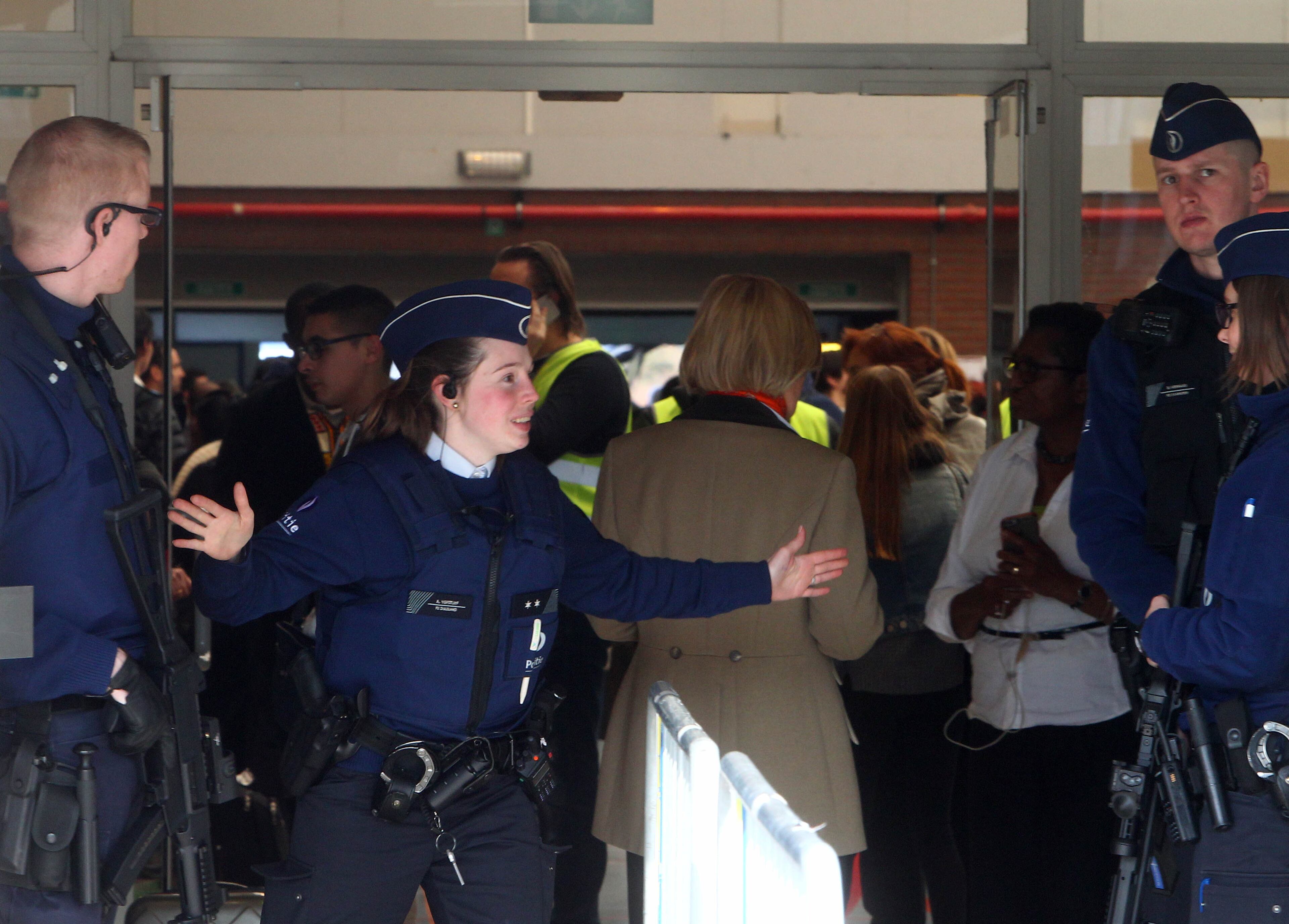 A police officer gestures outside a gym where passengers took shelter after the explosions, near the Zaventem Airport in Brussels, Tuesday, March 22, 2016. Bombs struck the Brussels airport and one of the city's metro stations Tuesday, killing and wounding dozens of people, as a European capital was again locked down amid heightened security threats. (AP Photo/Michel Spingler)