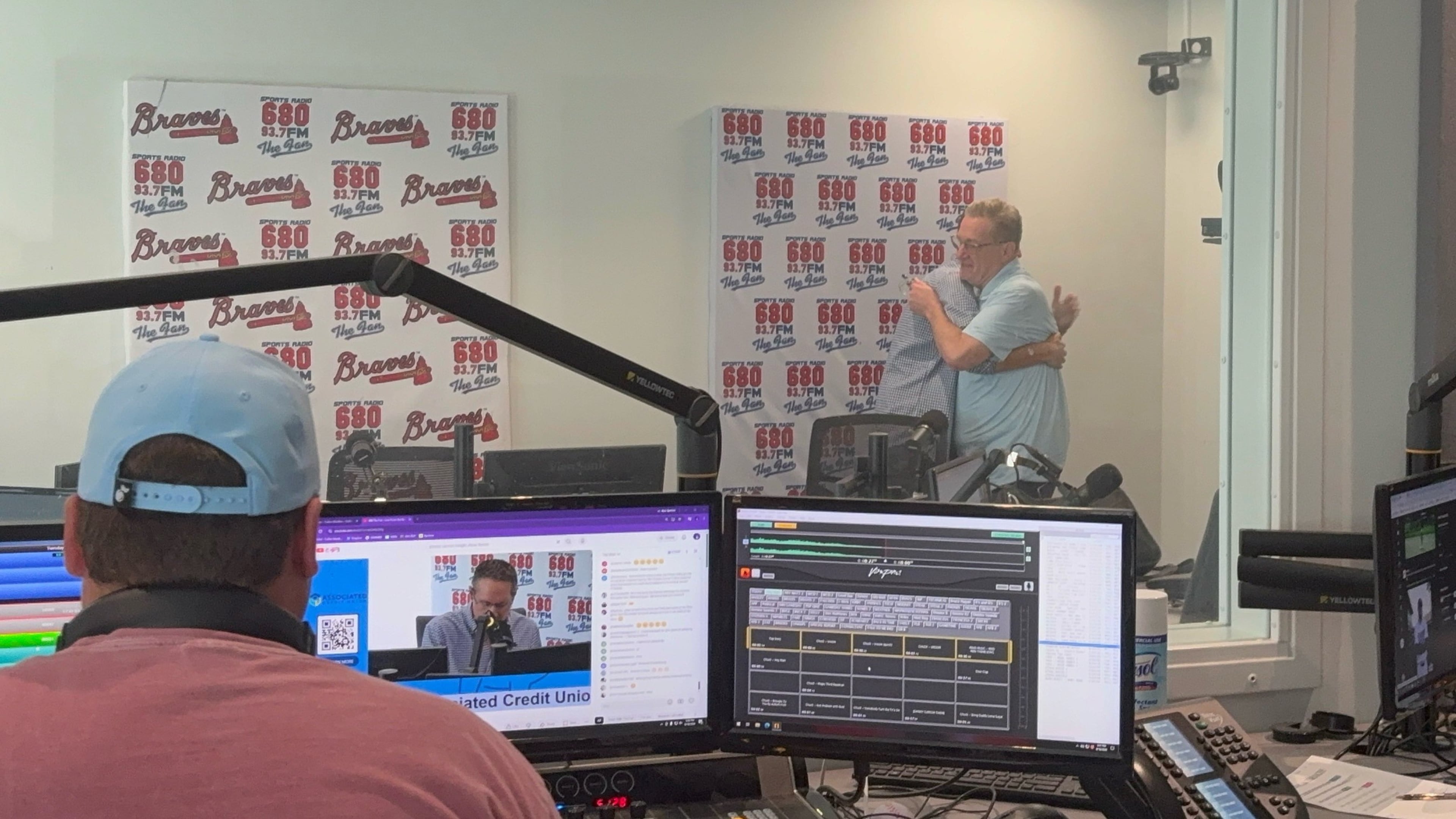 Moments after the final episode of the "Chuck and Chernoff" show on 93.7/680 The Fan wrapped up on Aug. 18, show hosts Chuck Oliver (right) and Matt Chernoff share a hug. Show producer Cullen Madden is in the foreground. (Ken Sugiura/AJC)