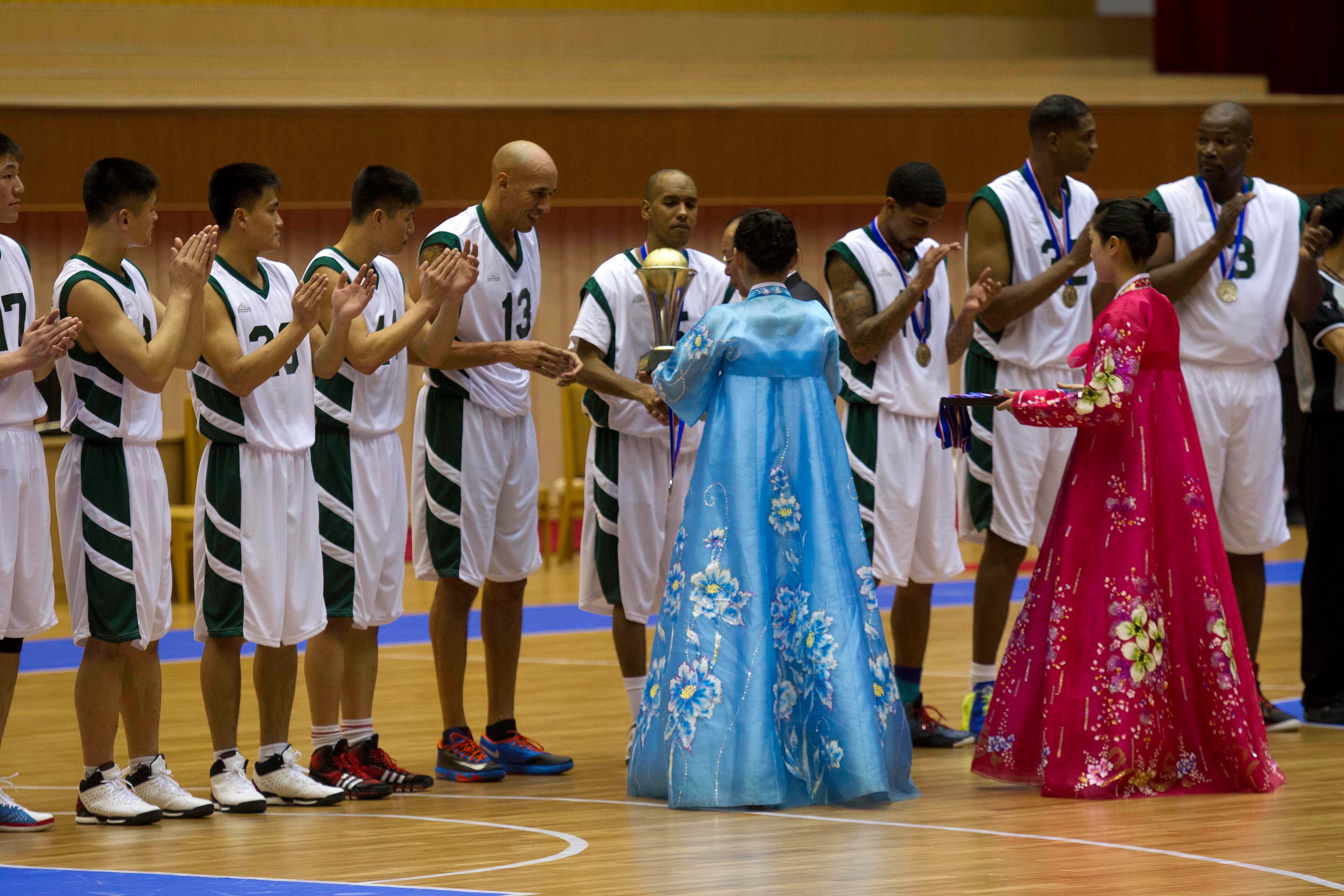 U.S. basketball player Doug Christie is handed a trophy as North Korean players applaud at the end of an exhibition basketball game at an indoor stadium in Pyongyang, North Korea on Wednesday, Jan. 8, 2014. The U.S. players, from left to right, are Christie, Andre "Silk" Poole, Guy Dupree, Charles D. Smith, and Cliff Robinson. (AP Photo/Kim Kwang Hyon)
