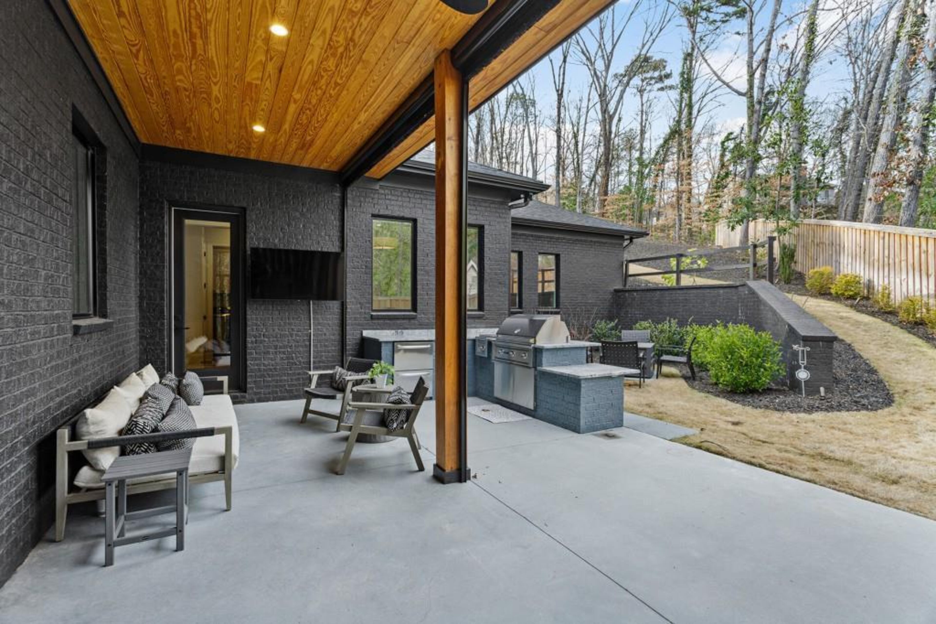 Covered back porch features automated screens, outdoor kitchen, and separate dining area.