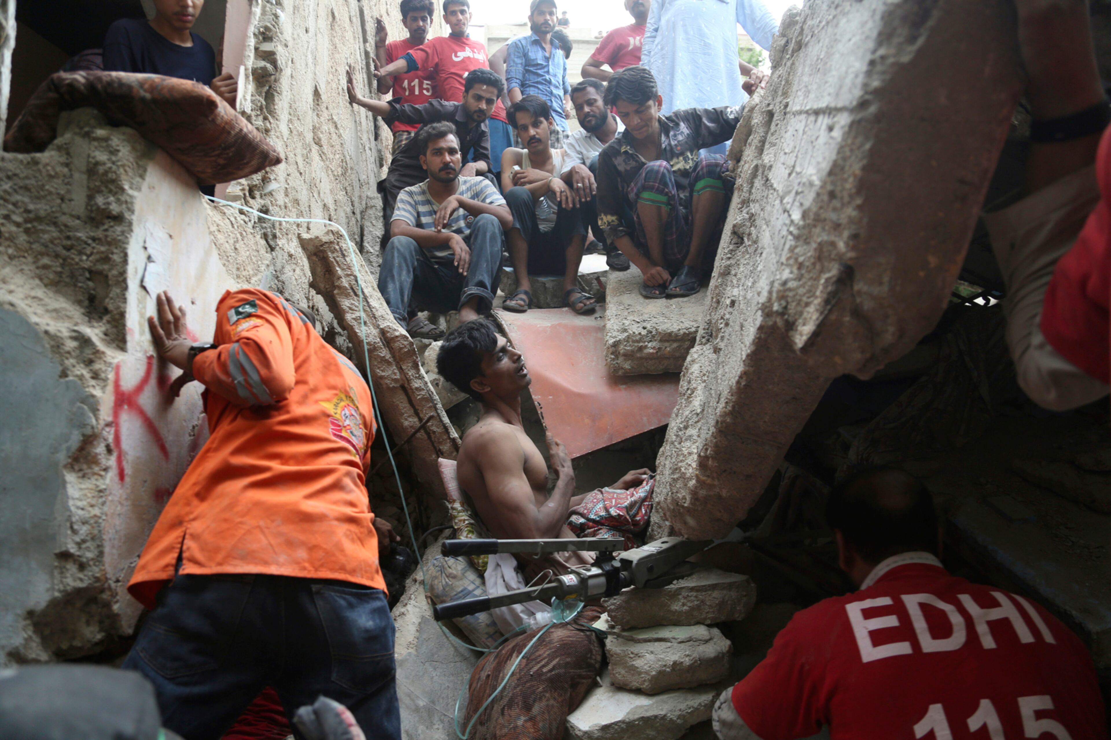 Pakistani volunteers try to rescue a trapped resident in Karachi, Pakistan, Tuesday, July 18, 2017. A dilapidated, three-story building in a poorer neighborhood of Pakistan's sprawling port city of Karachi collapsed as the residents slept. (AP Photo/Shakil Adil)