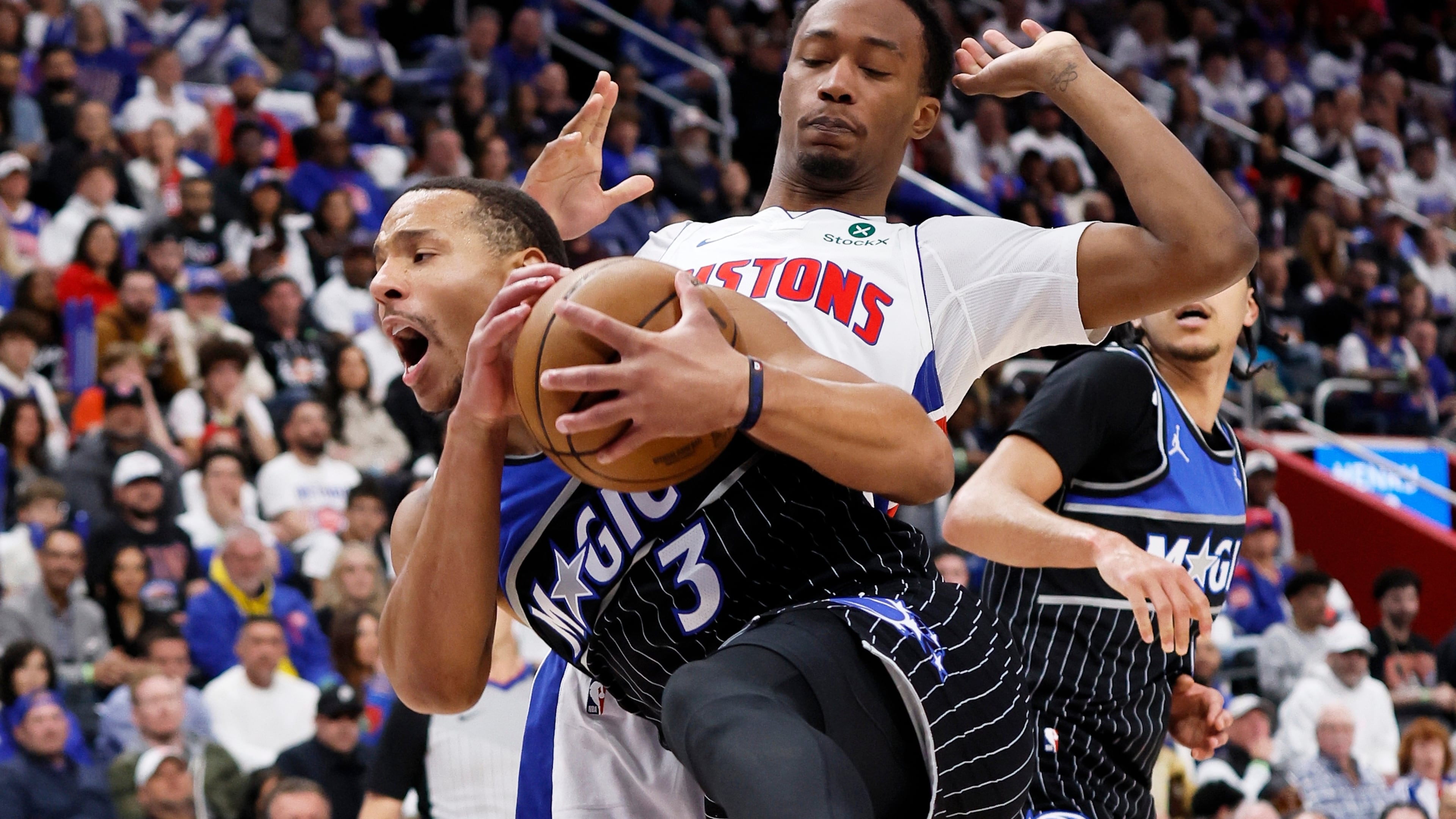 Orlando Magic guard Desmond Bane (3) grabs a rebound in front of Detroit Pistons forward Ronald Holland II, top right, during the first half in Game 1 of a first-round NBA basketball playoffs series Sunday, April 19, 2026, in Detroit. (AP Photo/Duane Burleson)